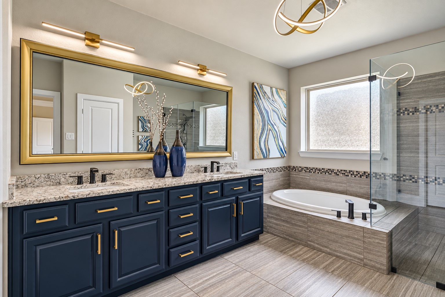 The updated primary bath pairs a long dual-sink granite vanity with rich navy cabinetry, gold hardware, oversized framed mirror and modern lighting, plus a soaking tub and oversized seamless-glass shower.