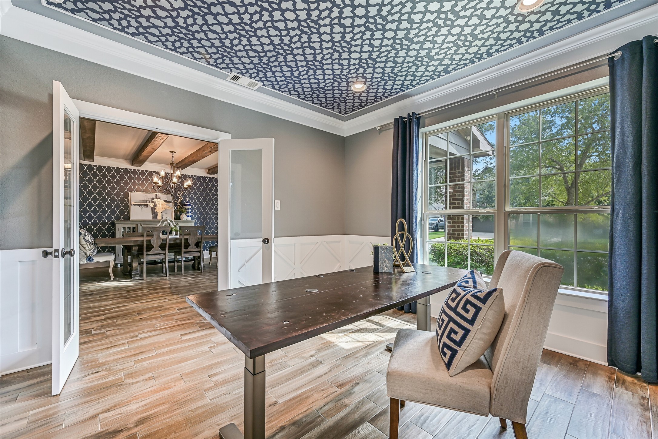 Just across the foyer, the private study is finished with double glass doors for privacy, easy to maintain wood-look tile flooring, extensive custom millwork, recessed lighting, and added interest from a patterned trayed ceiling.