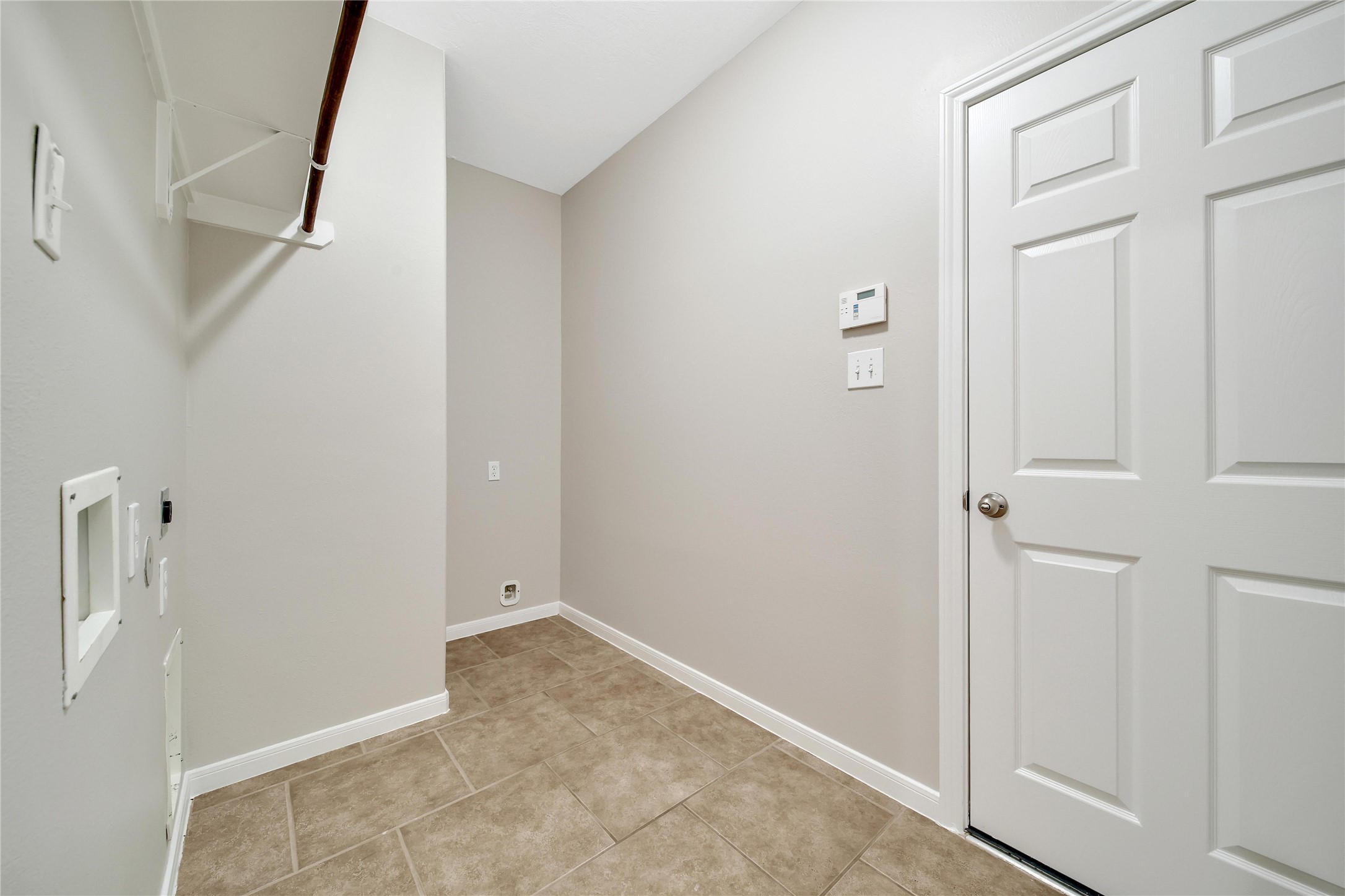 Spacious laundry room with hanging rack and room for a second fridge is located at the end of the split plan hall and has access to the garage.