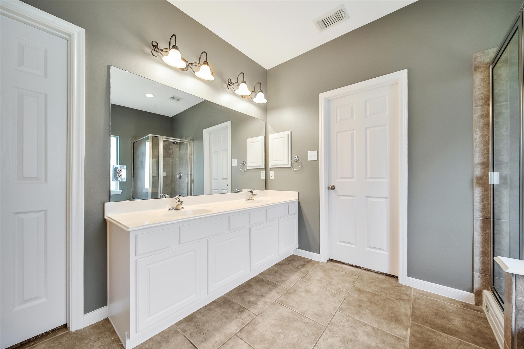 The Primary bathroom features double sinks on the spacious vanity with a huge mirror with overhead lighting and recessed.