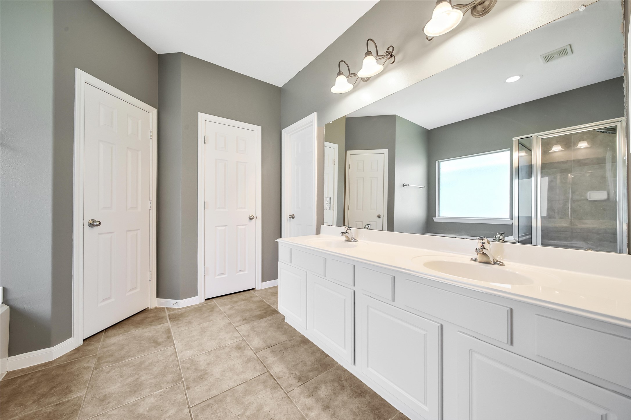 The Primary bathroom features double sinks on the spacious vanity with a huge mirror with overhead lighting and recessed.