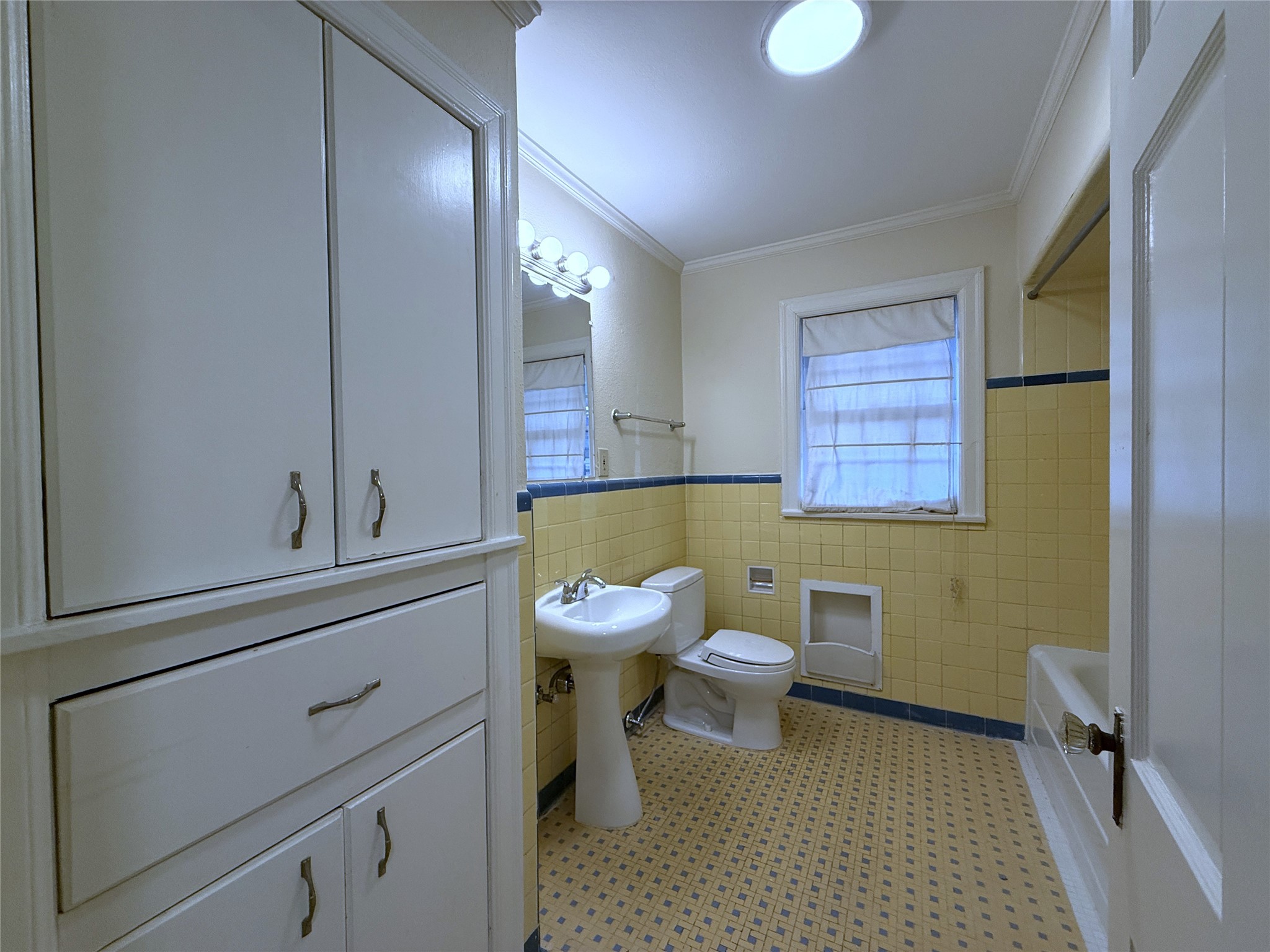 The hallway bath features vintage tile, tub/shower combo, linen storage & built-in hamper.