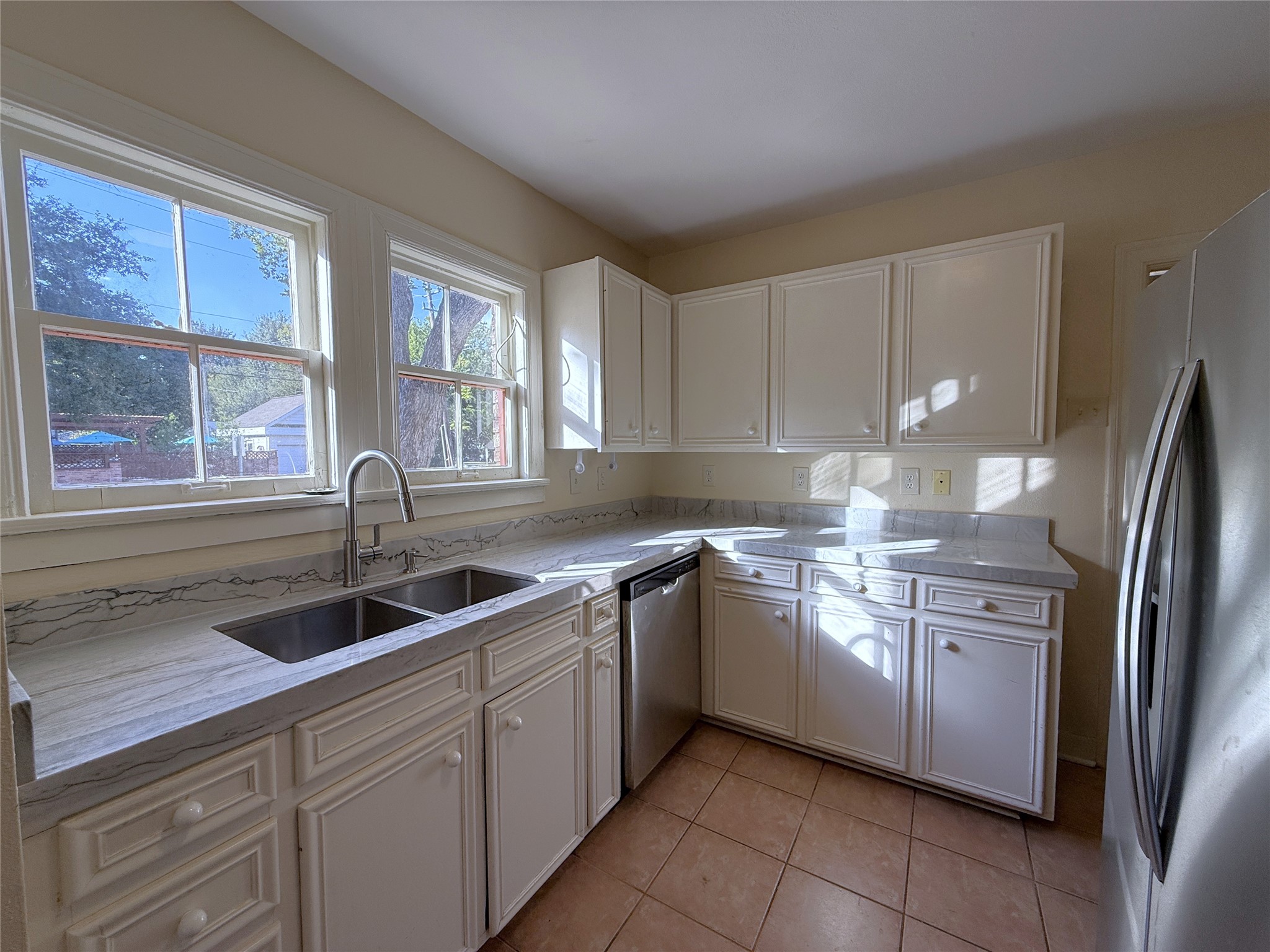 Stone counter tops, dishwasher, deep double sink and lots of cabinet space. Natural light flows in from twin windows.