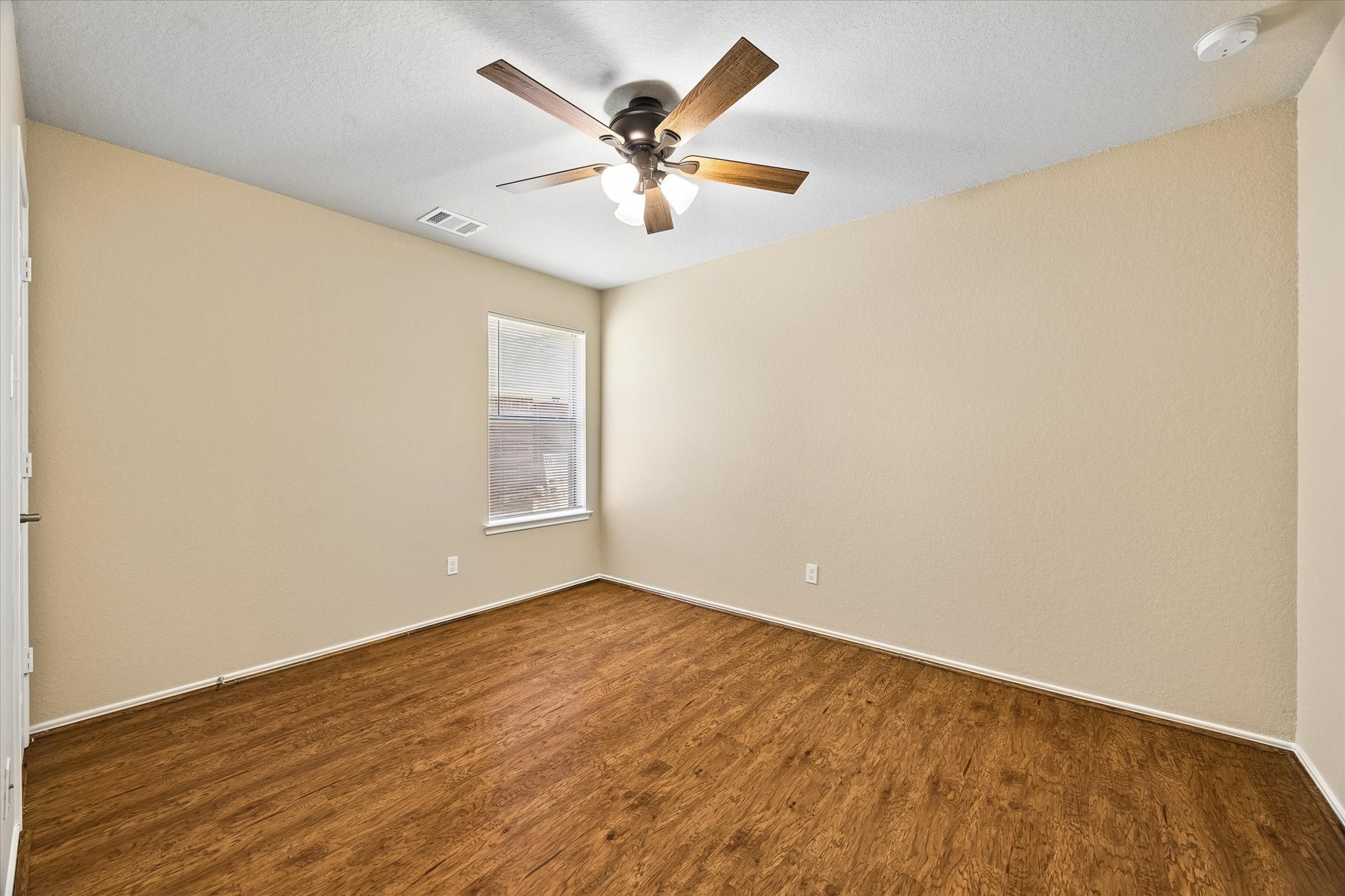 Additional bedroom with neutral finishes, wood-look flooring, and updated ceiling fan. Flexible space for guests, hobbies, or a home office.