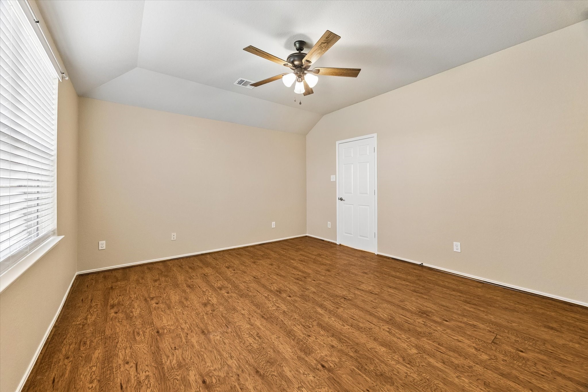 Spacious primary suite featuring a NEW ceiling fan, wood-look flooring, and fresh interior paint.
