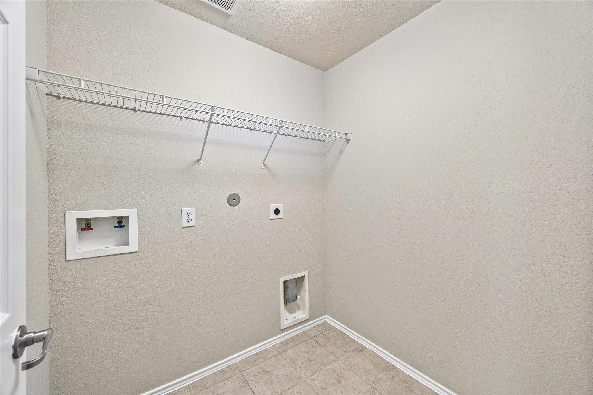 Dedicated interior laundry room with washer and dryer connections and overhead storage shelving.