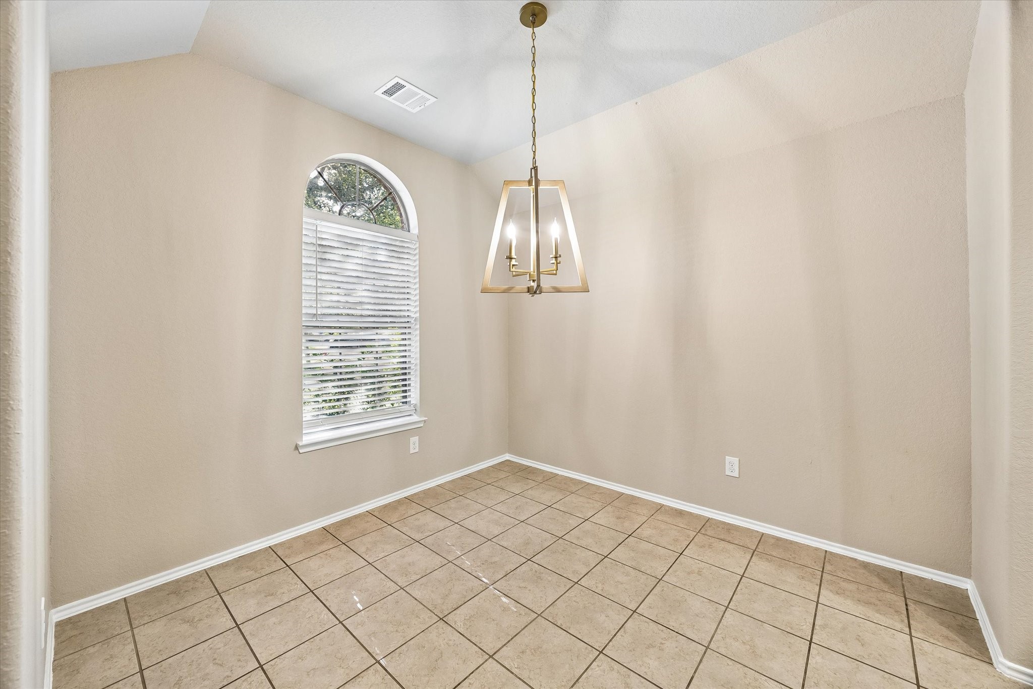 Dining room featuring a vaulted ceiling, beautiful arched window, and newly updated chandelier. Perfect for hosting dinners and holiday gatherings.