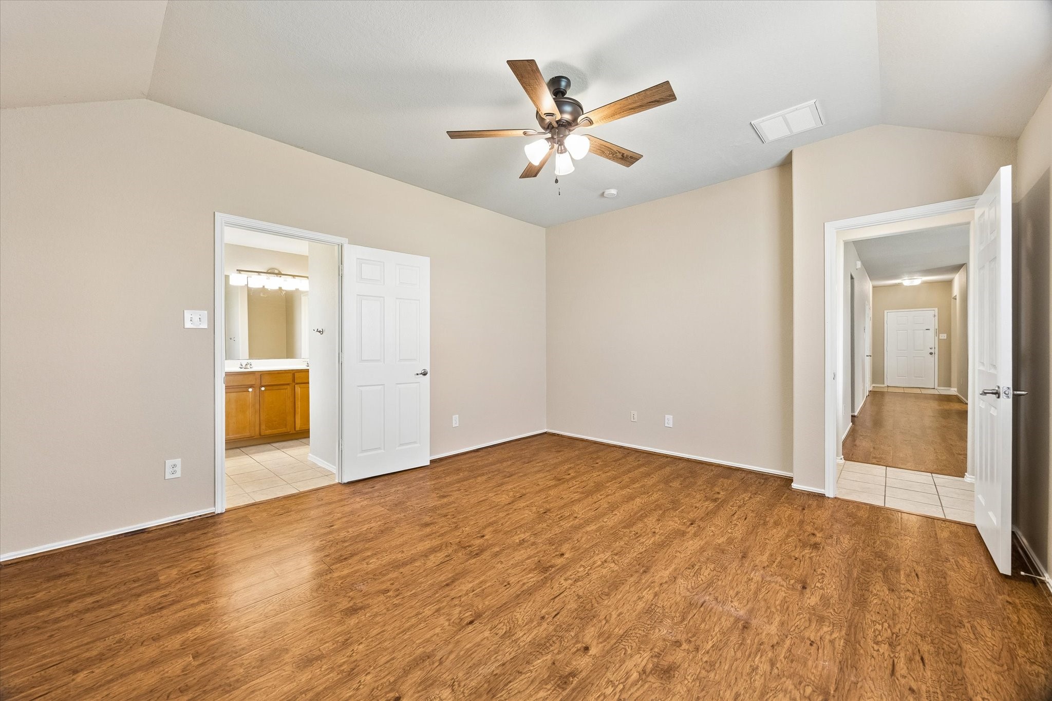 Another view of the primary suite showcasing the comfortable layout, neutral finishes, and convenient access to the private bathroom.