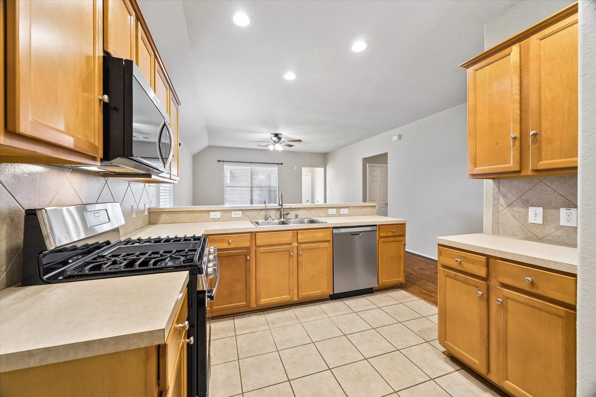 Warm wood cabinetry, stainless steel appliances, and generous counter space make this kitchen both functional and inviting.