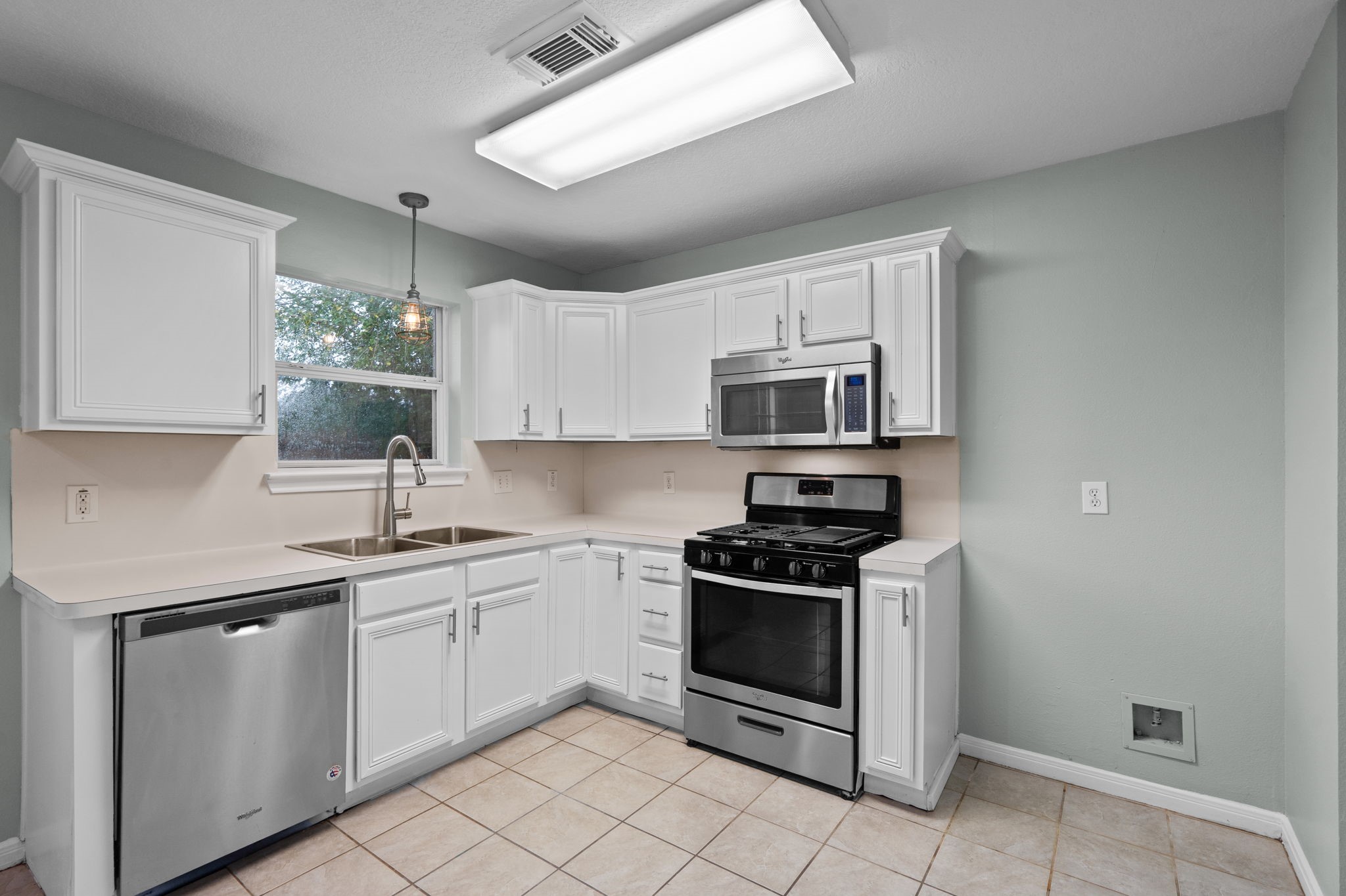 Bright kitchen with modern stainless steel appliances, white cabinetry, and ample counter space.
