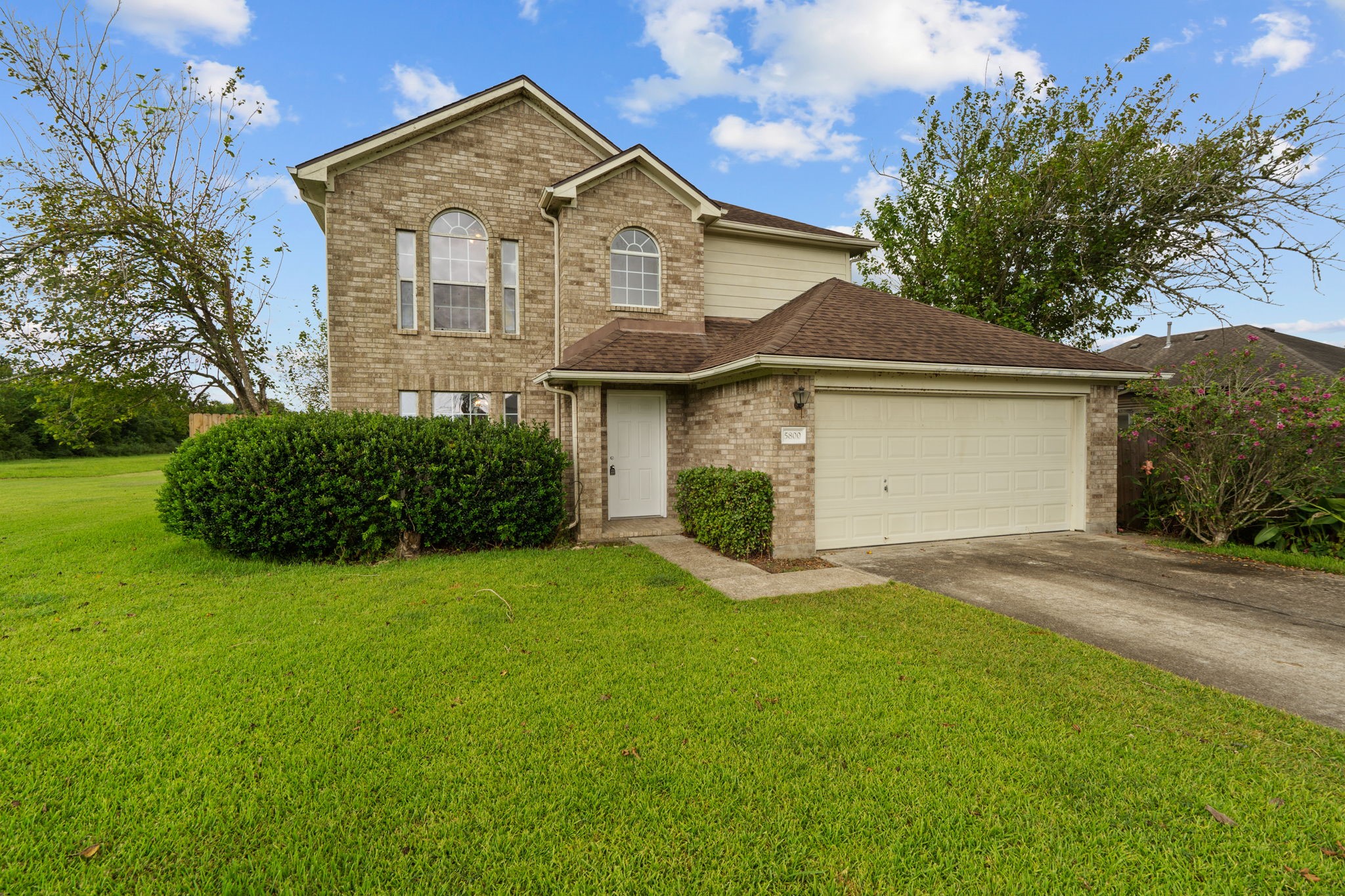 Charming two-story brick home with a spacious two-car garage, surrounded by lush greenery and a well-maintained lawn. Charming two-story brick home with a spacious two-car garage, surrounded by lush greenery and a well-maintained lawn.