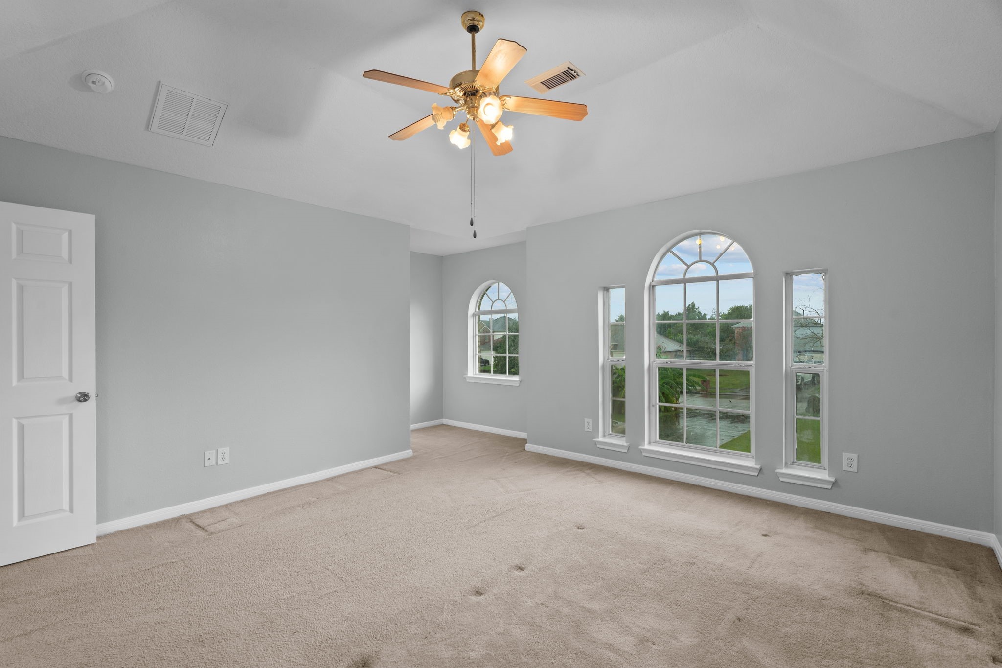 Bright and spacious bedroom with vaulted ceilings, featuring elegant arched windows that offer scenic views and fill the room with natural light.