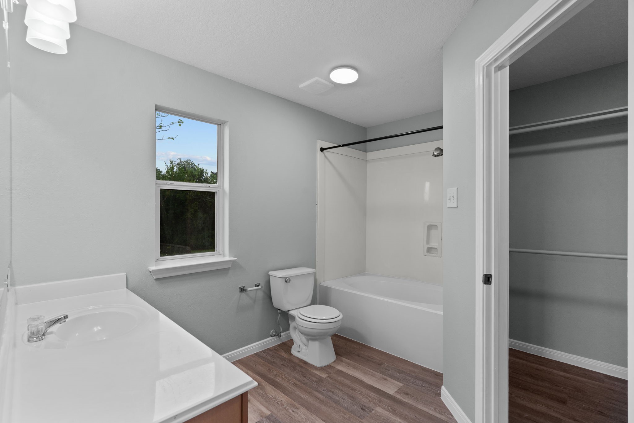 Bright and spacious bathroom featuring a sleek vanity, modern fixtures, and a full bathtub with shower.