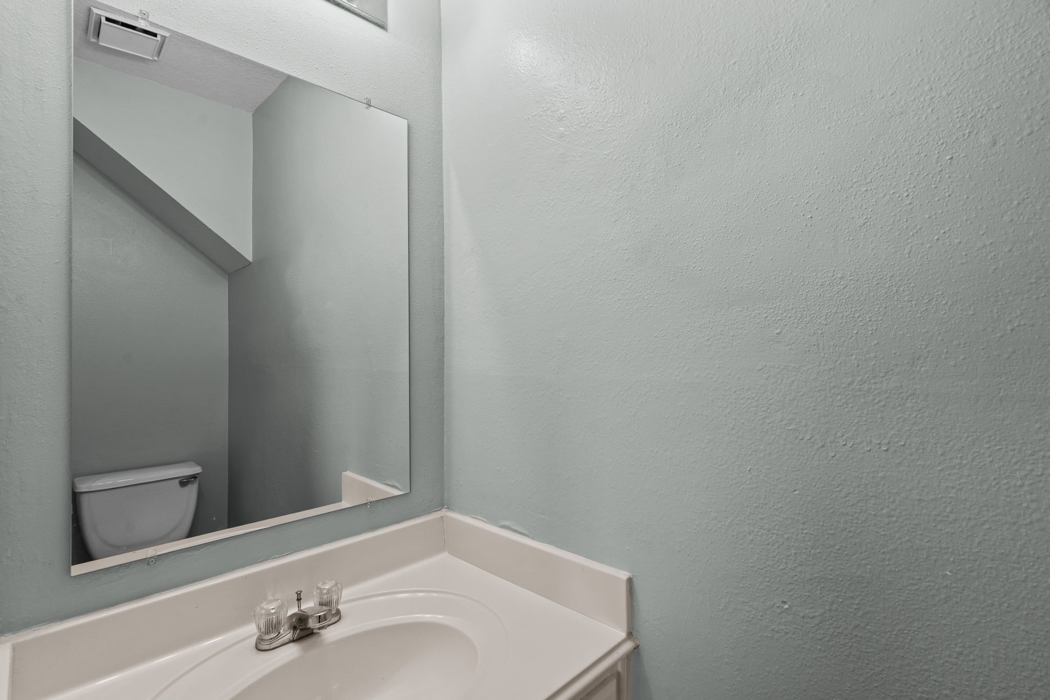 Compact half-bathroom with a sleek mirror, modern sink, and soft gray walls.