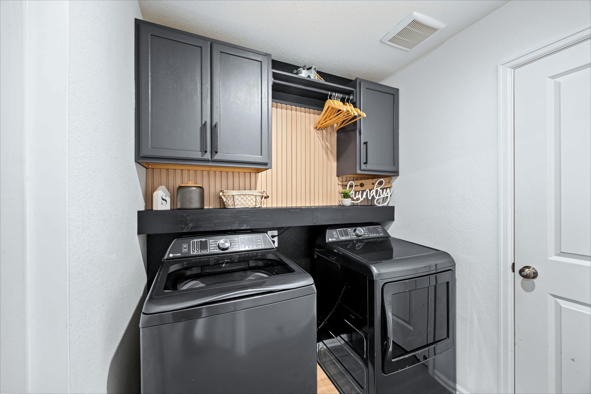 Laundry room with built-in cabinets and a hanging rod