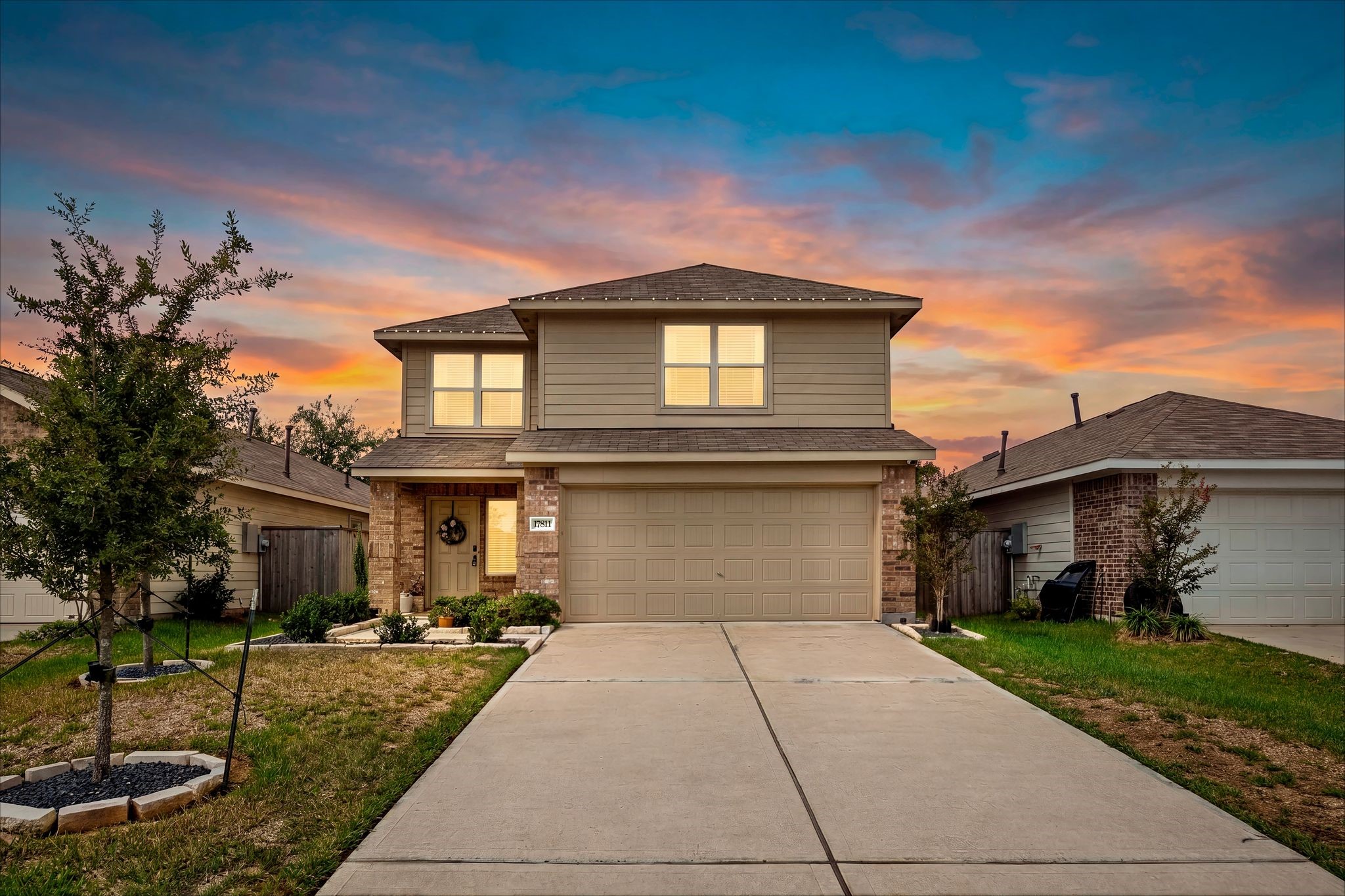 Twilight view of the front with a warm glow and a wide driveway