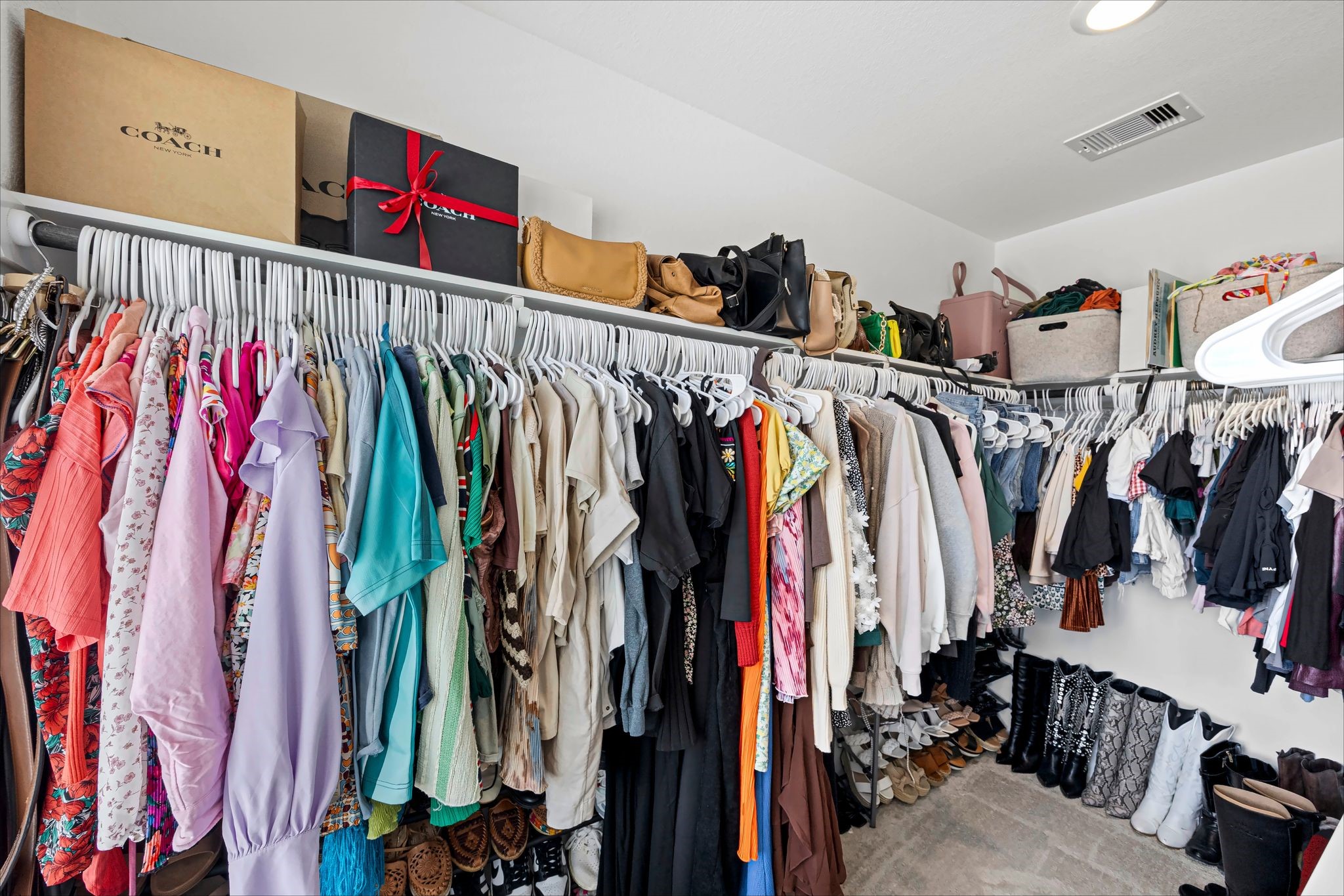 Primary walk-in closet with plenty of hanging and shelf space