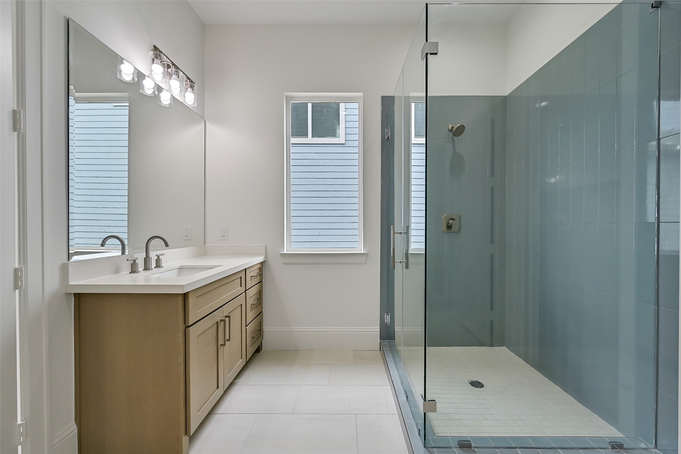 Gorgeous blue tile surrounds the shower, adding a beautiful pop of color and coastal charm to the space.