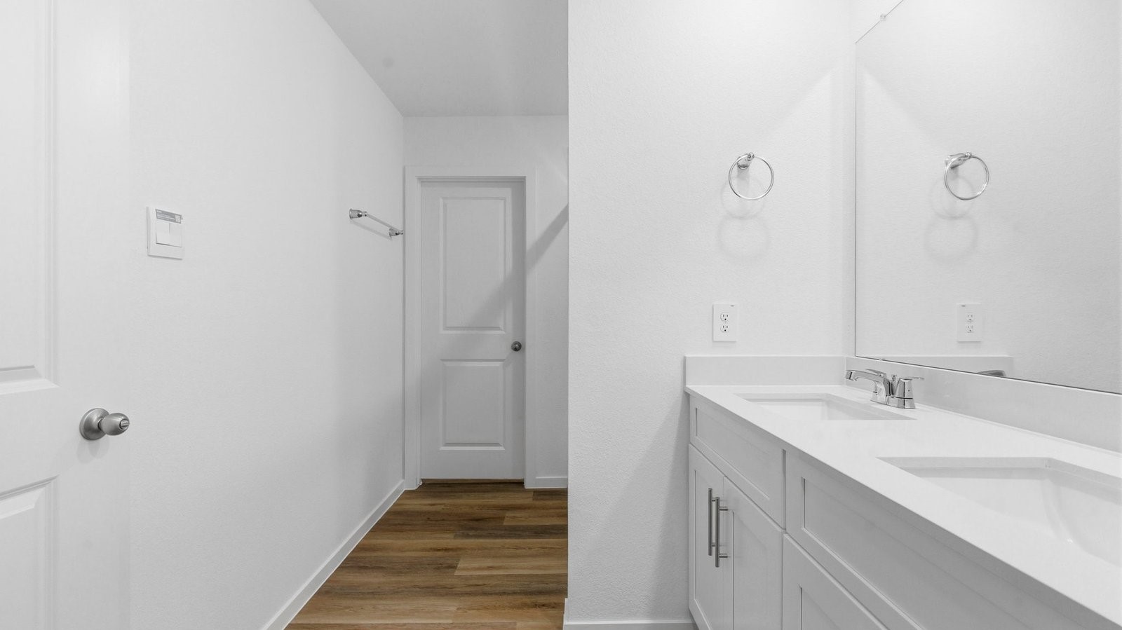 Modern primary bathroom with double vanities, quartz countertops, and a glass-enclosed shower with a walk-in closet.