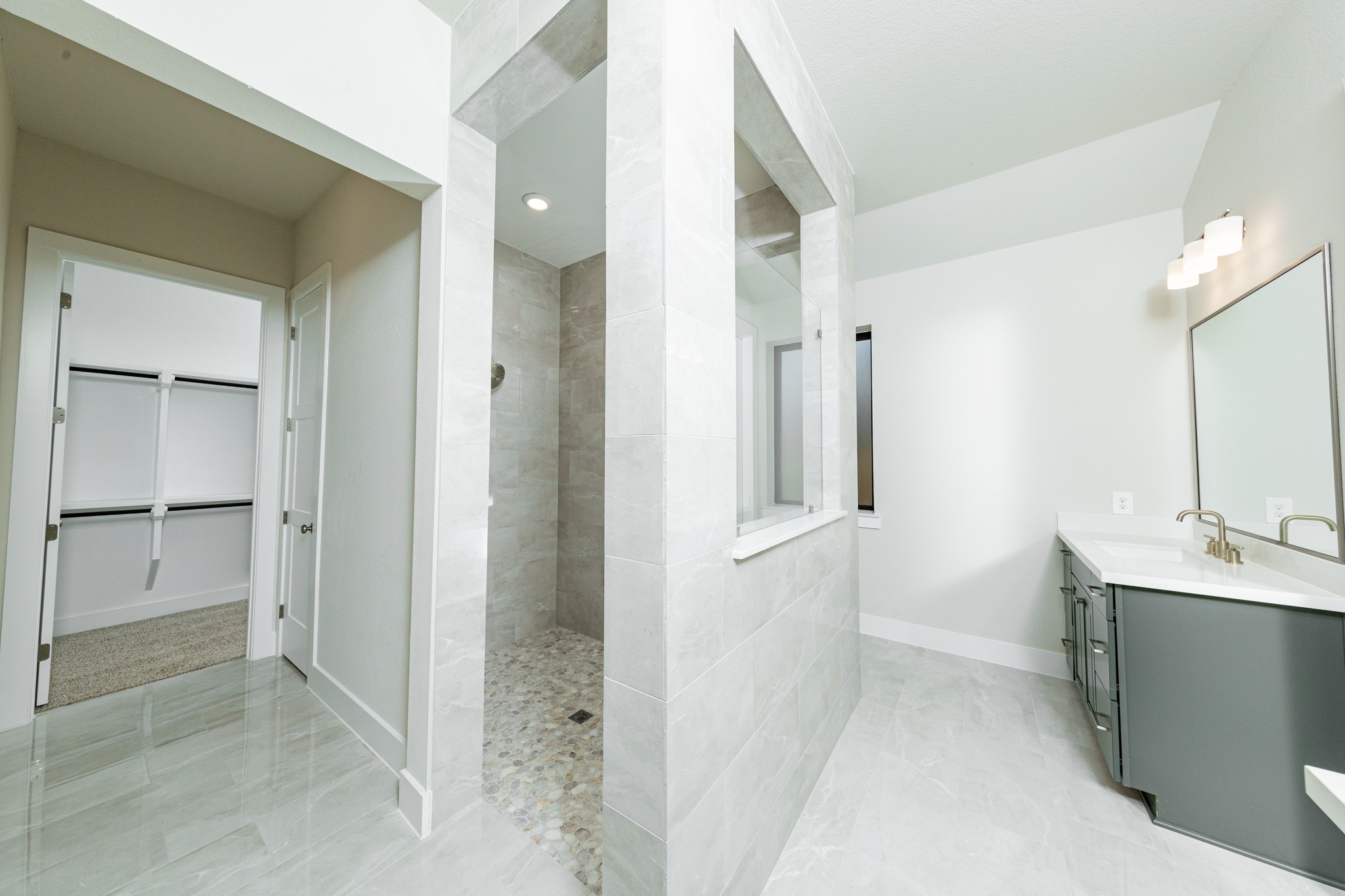 The walk-in shower boats of stylish tile surround and a pebble mosaic tile flooring.