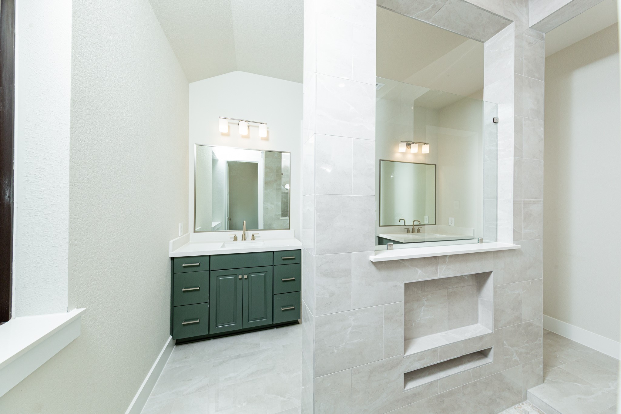 Additional view of the primary bathroom vanity area and open walk-in shower.