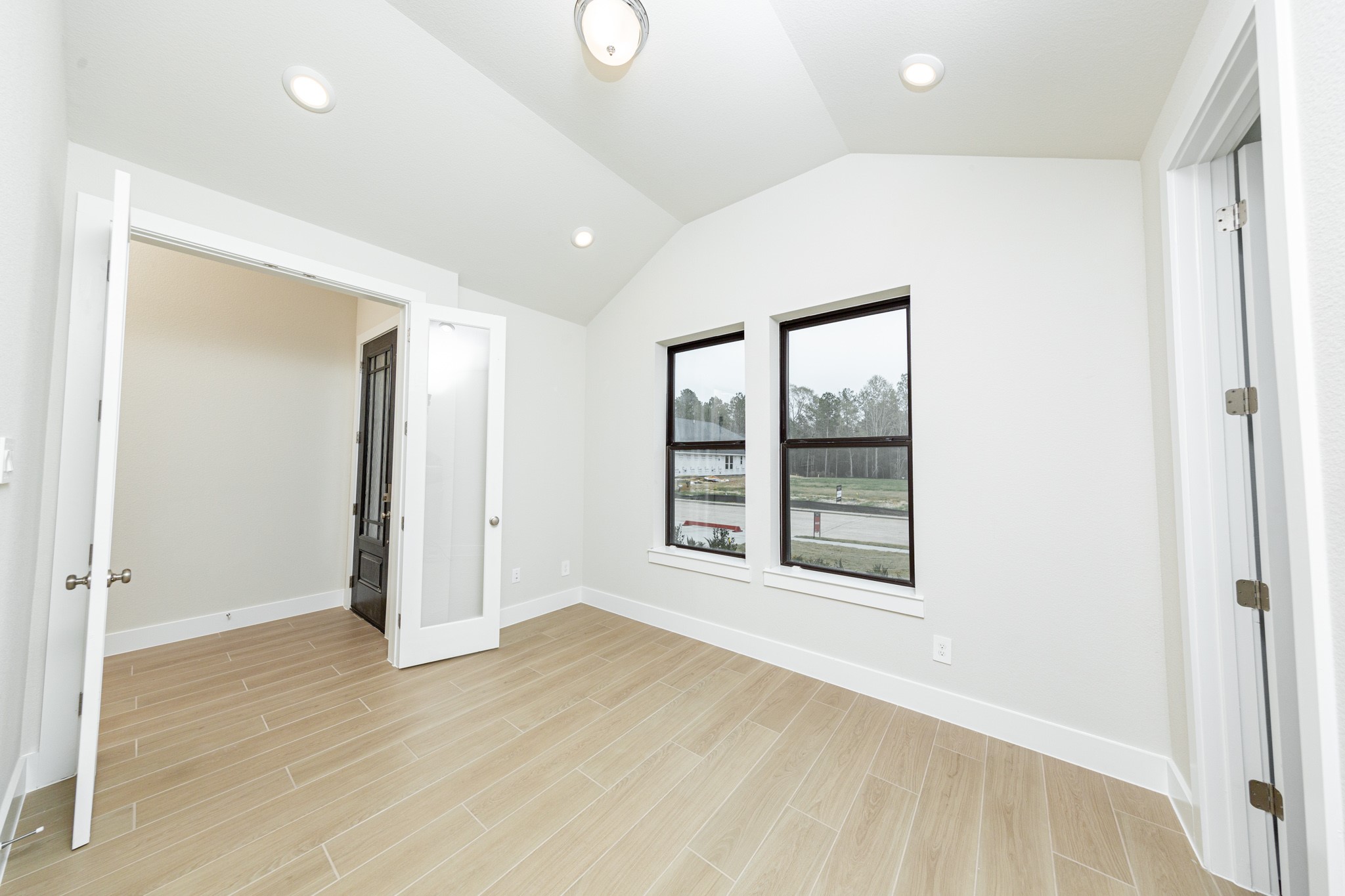 Tucked peacefully in the front of the home is this study, which features large windows, tile flooring, French doors, and neutral toned walls.
