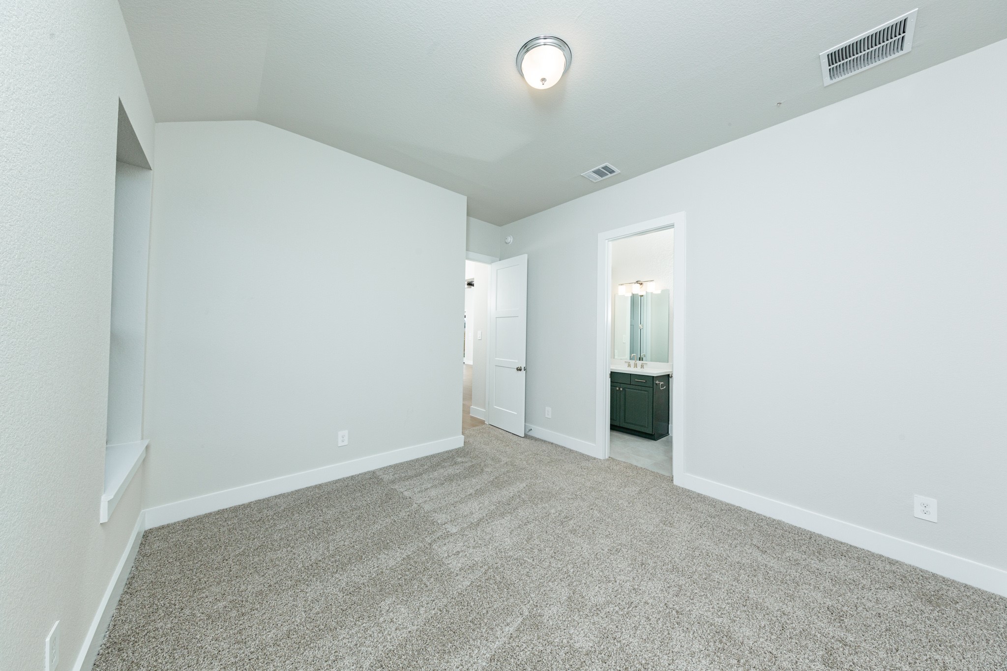 This inviting secondary bedroom would make a wonderful guest suite! Featuring a soft neutral color palette, large window, walk-in closet, and an ensuite secondary bathroom.