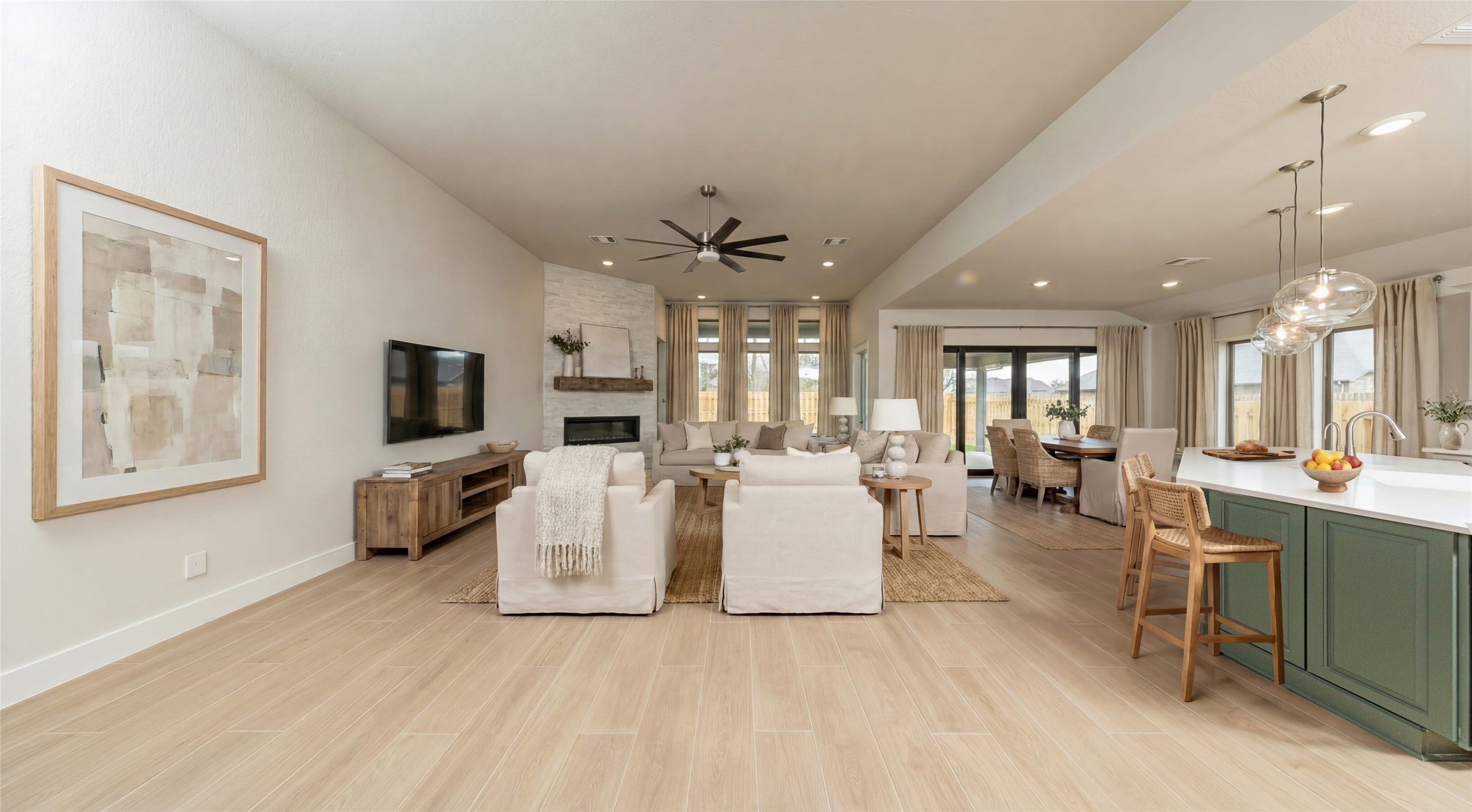 Enjoy an open, airy living experience! The Great Room features a stunning electric fireplace with stacked stone - floor to ceiling. The oversized windows flood the entire space with abundant natural light and frame a picturesque view of the serene backyard. A large ceiling fan provides comfort all year long. *Virtually Staged