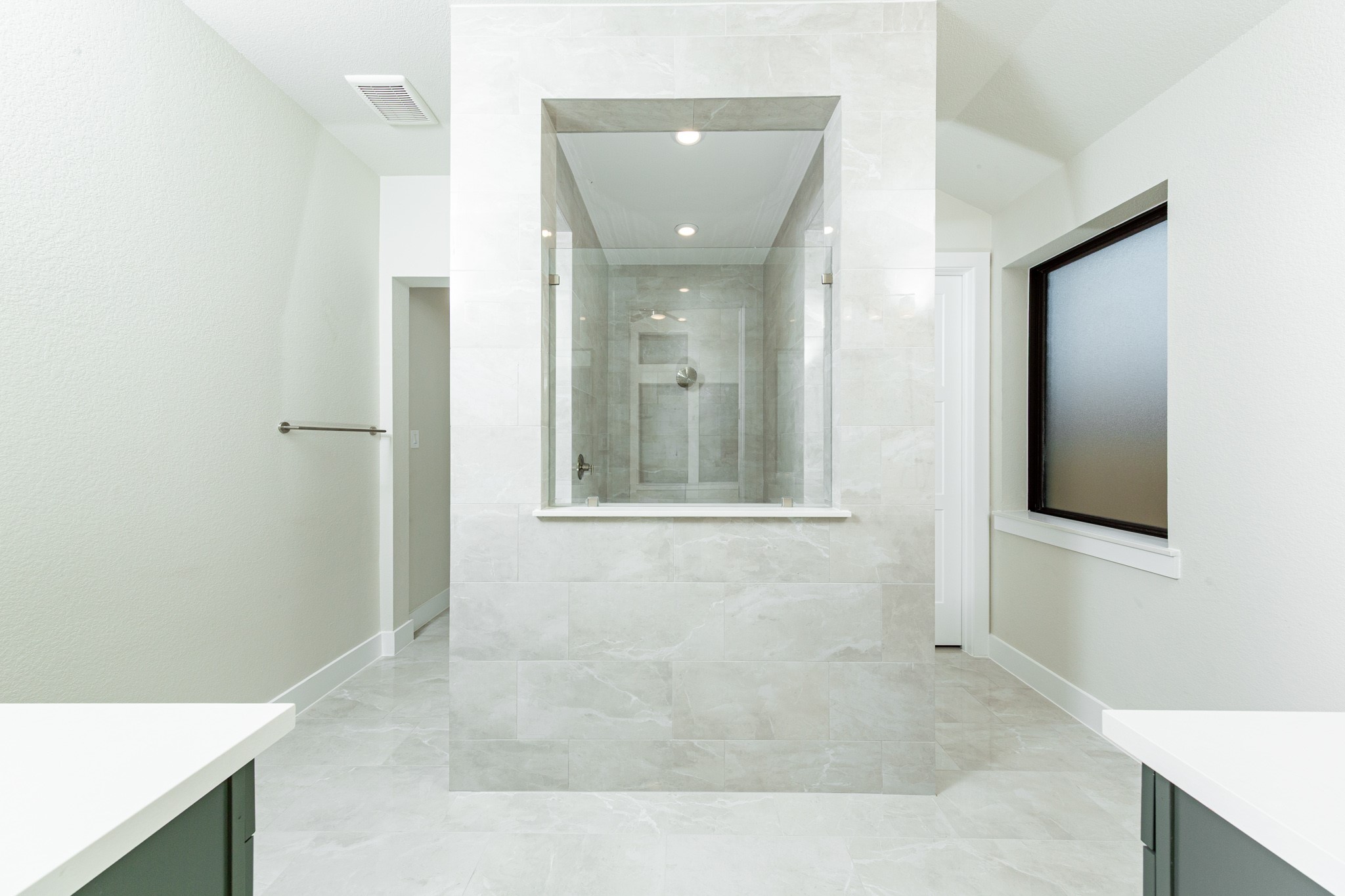 This stunningly updated primary bathroom is truly move-in ready! It features a large walk-in shower with tile surround, stained cabinetry with light countertops, dual vanities, mirrors, a generous walk-in closet with built-in shelving, soaring ceilings, custom paint, and sleek modern fixtures.