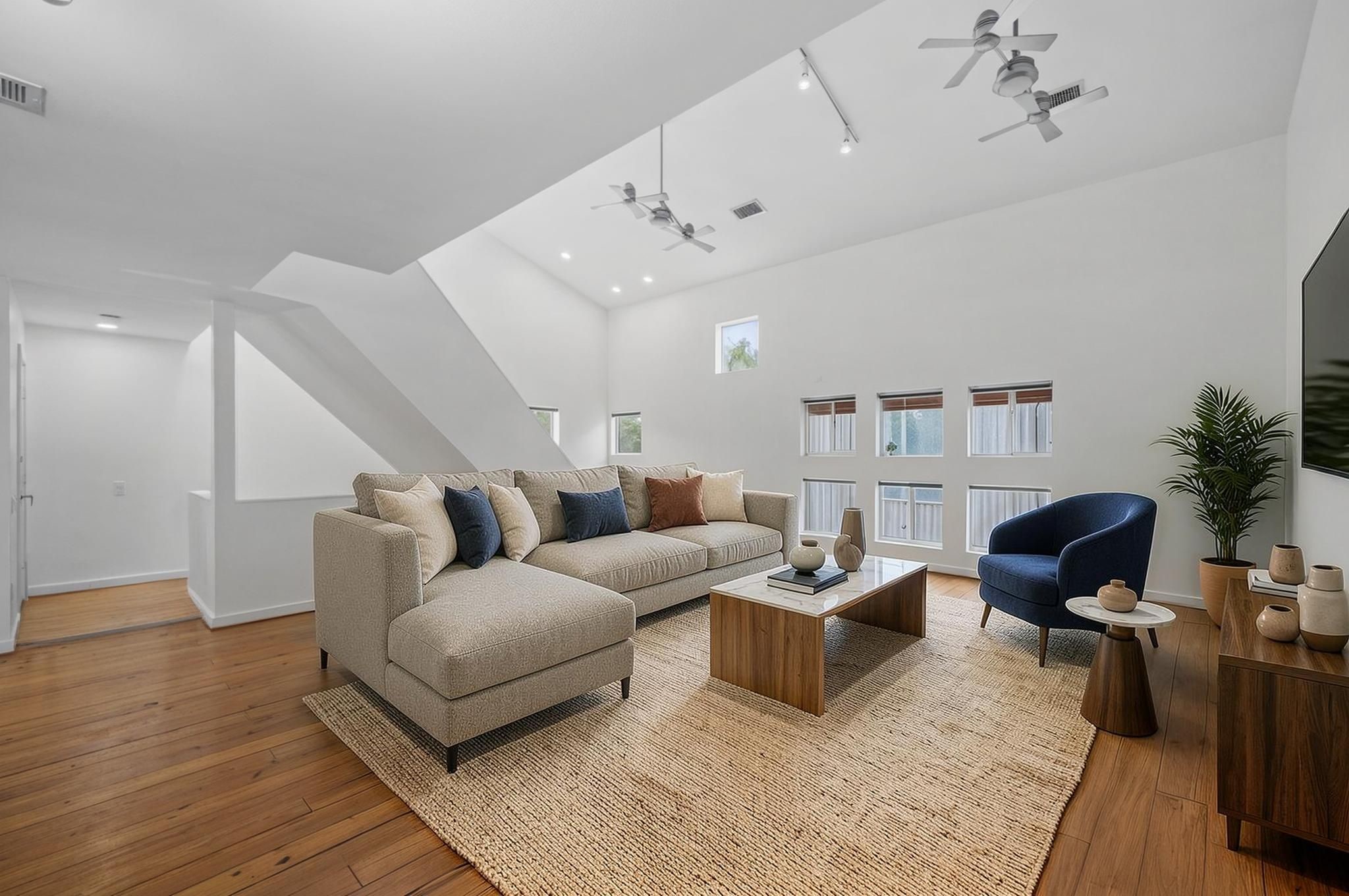 The second-floor living room opens with soaring ceilings, hardwood floors, oversized windows, and strong natural light. The space feels elevated, open, and connected to the dining and kitchen areas. Virtually staged. The second-floor living room opens with soaring ceilings, hardwood floors, oversized windows, and strong natural light. The space feels elevated, open, and connected to the dining and kitchen areas. Virtually staged.