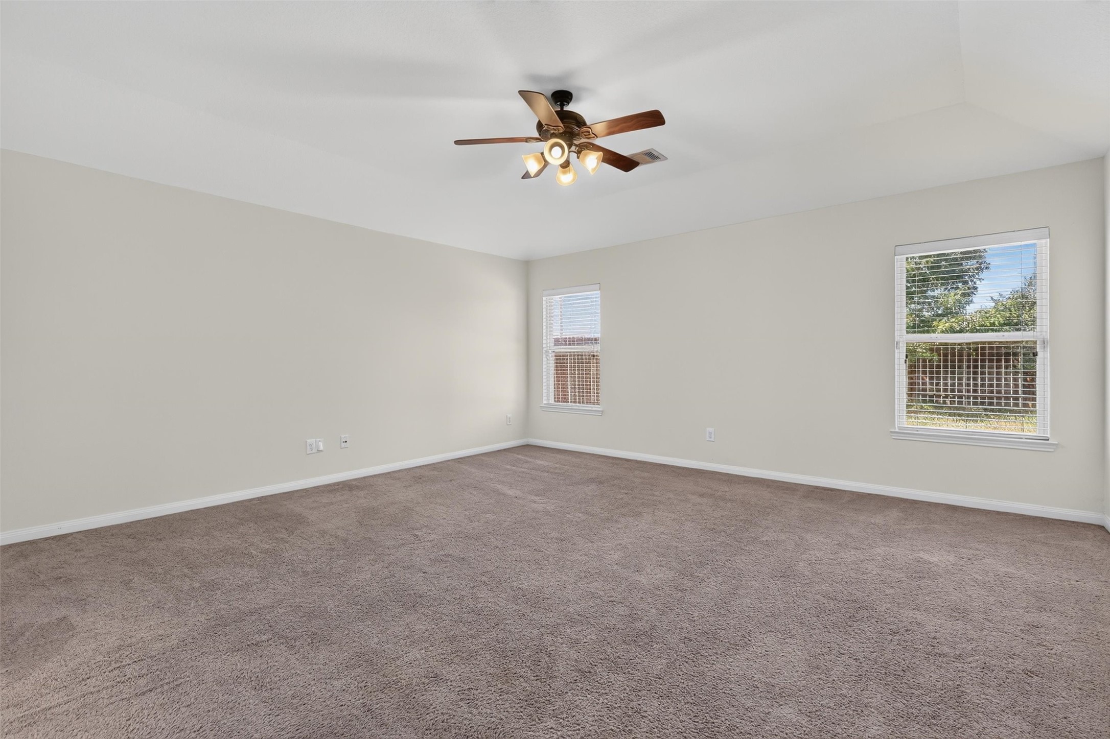Unwind in this inviting bedroom, where two windows welcome natural light and neutral tones create a soothing backdrop for your personal style. Soft carpeting and a ceiling fan add everyday comfort, while the generous layout offers flexibility for bedroom furnishings and a cozy reading nook. An appealing retreat for slow mornings and restful evenings.