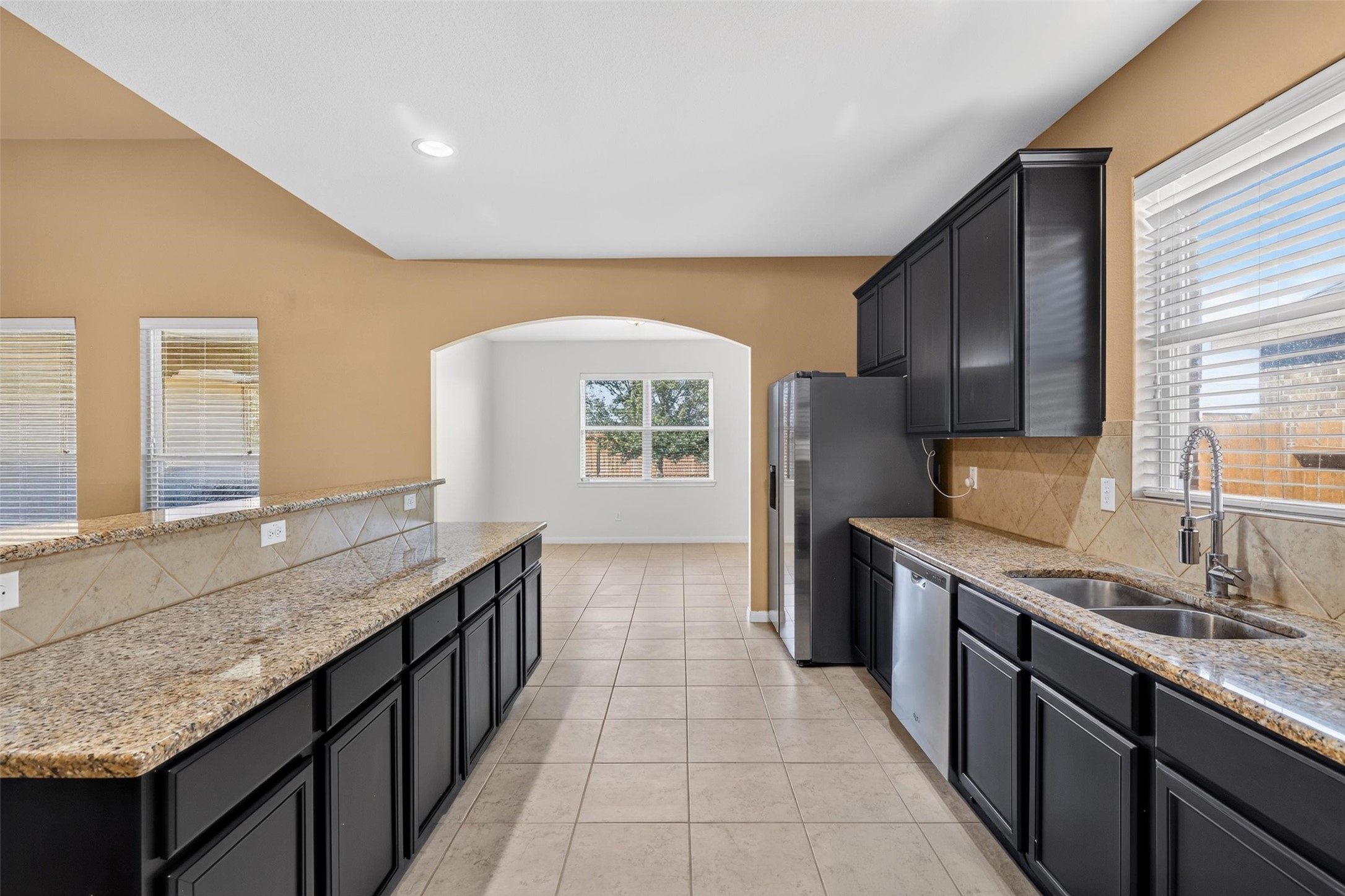 Expansive counters, abundant dark cabinetry, and a raised breakfast bar offer plenty of space for meal preparation, storage, and casual dining.