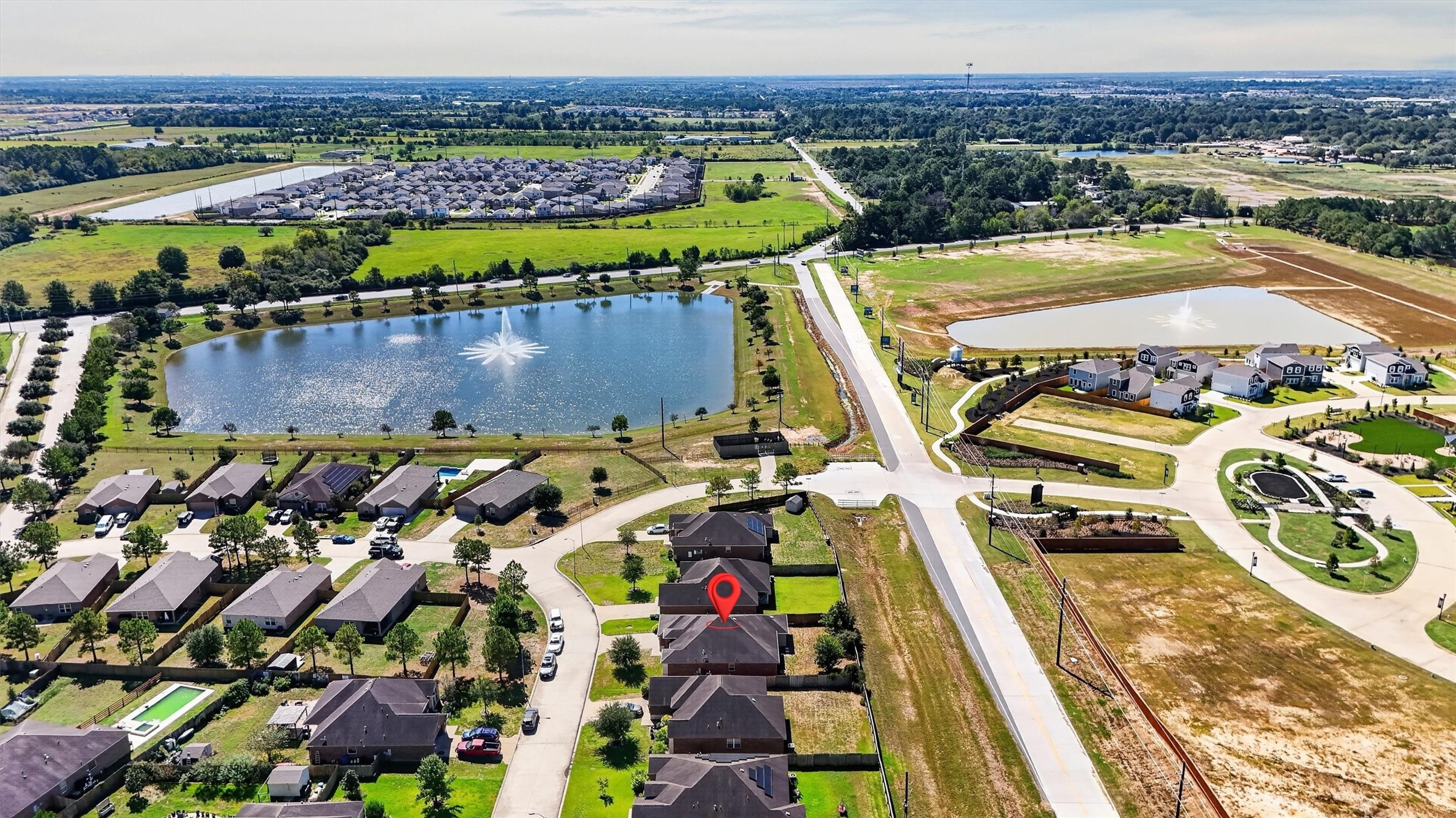 A fresh perspective on a welcoming neighborhood! This aerial view highlights the homes location along a curved residential street, with no home directly behind the property. A nearby pond with a striking fountain, tree-lined edges, and surrounding green space adds scenic appeal. The wider view showcases the neighborhood layout and surrounding area, giving you a sense of where your next chapter could begin.