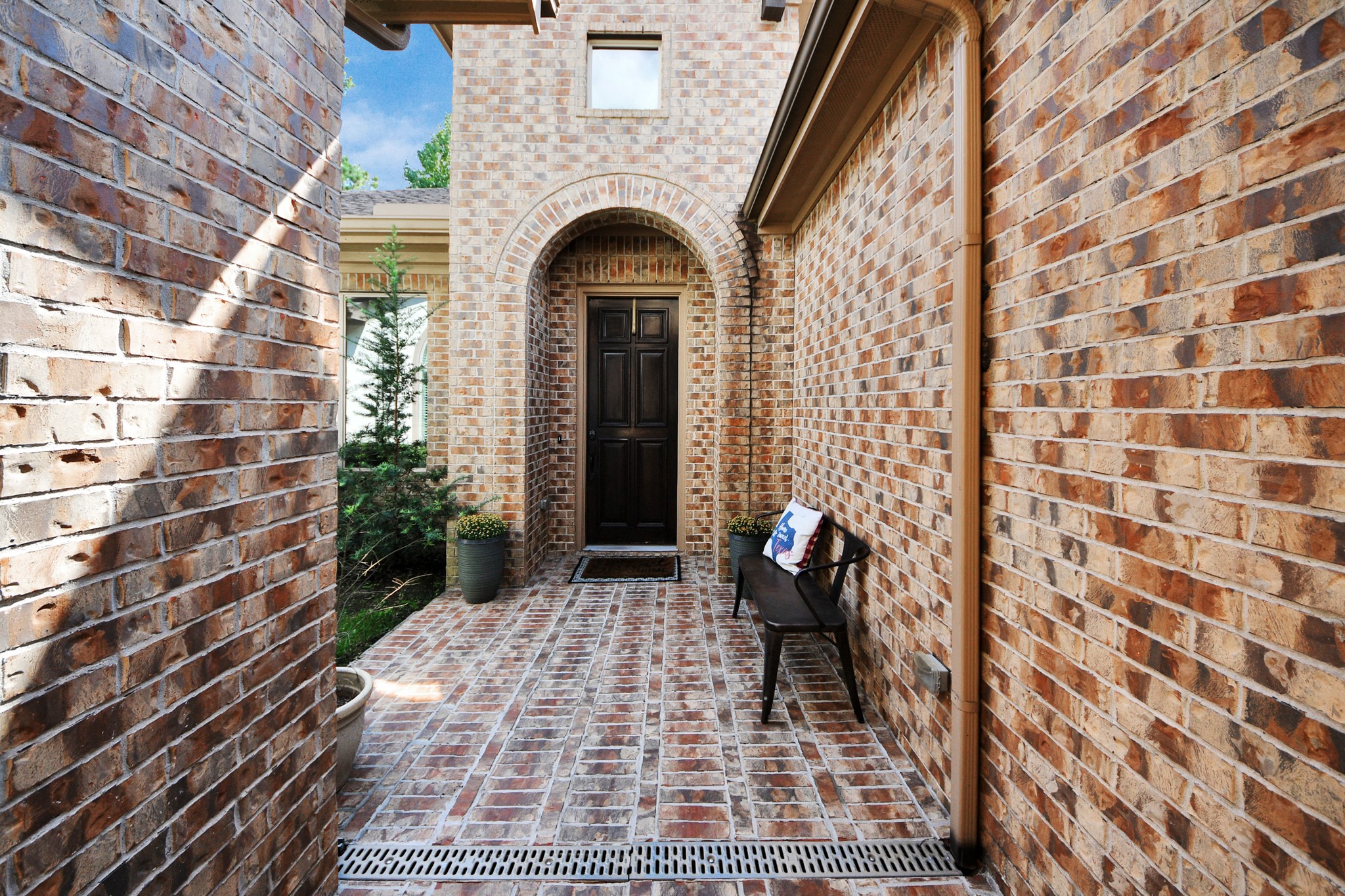 Charming brick entryway with a welcoming arch and cozy bench, leading to a classic dark wood front door. Charming brick entryway with a welcoming arch and cozy bench, leading to a classic dark wood front door.
