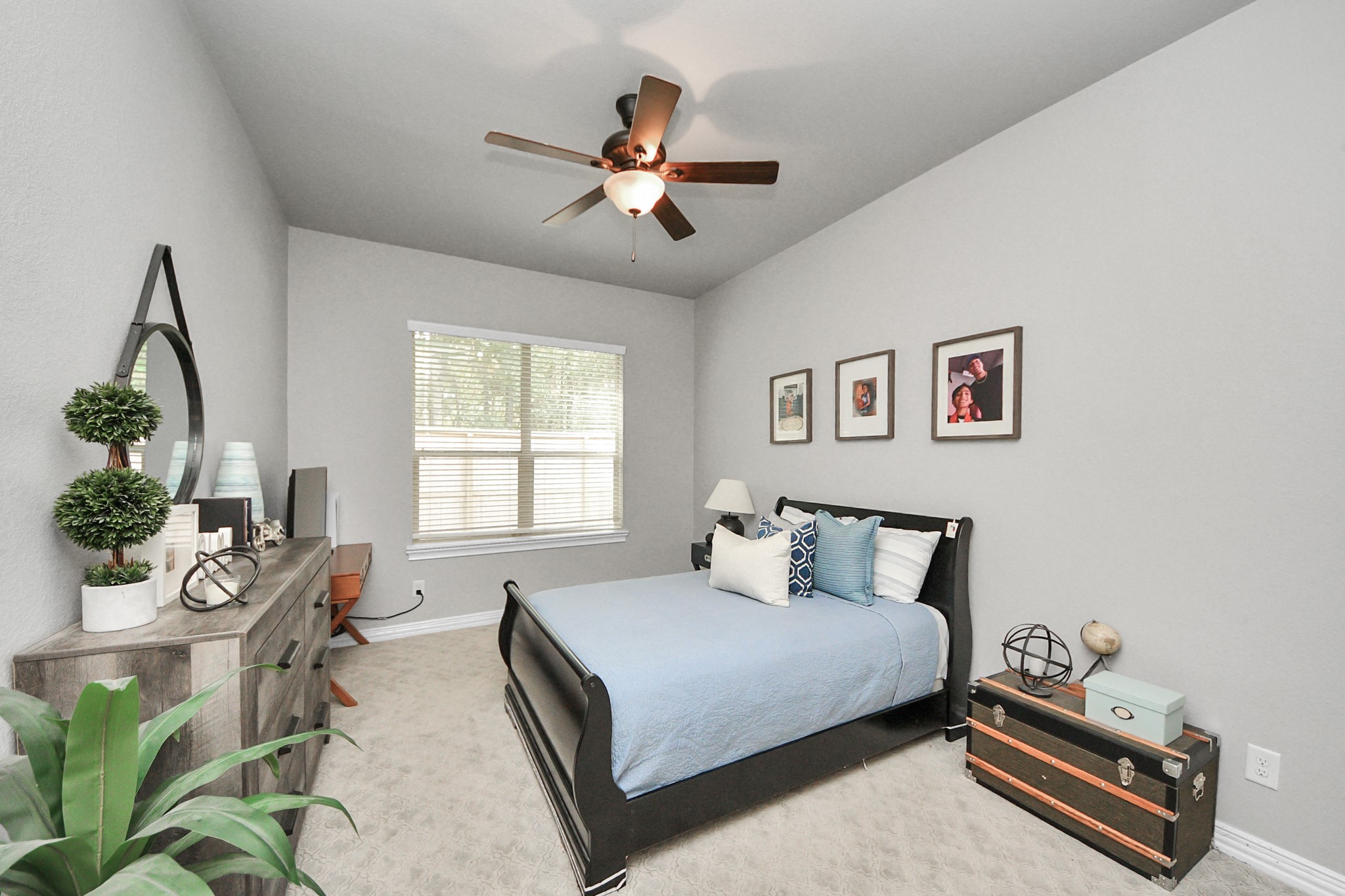 Cozy bedroom featuring a stylish dark bed frame, modern decor, and ample natural light from a large window.