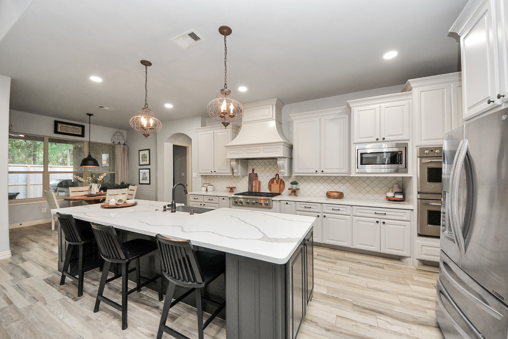 Spacious kitchen featuring elegant white cabinetry, a large marble island with seating, and modern stainless steel appliances, perfect for culinary enthusiasts.