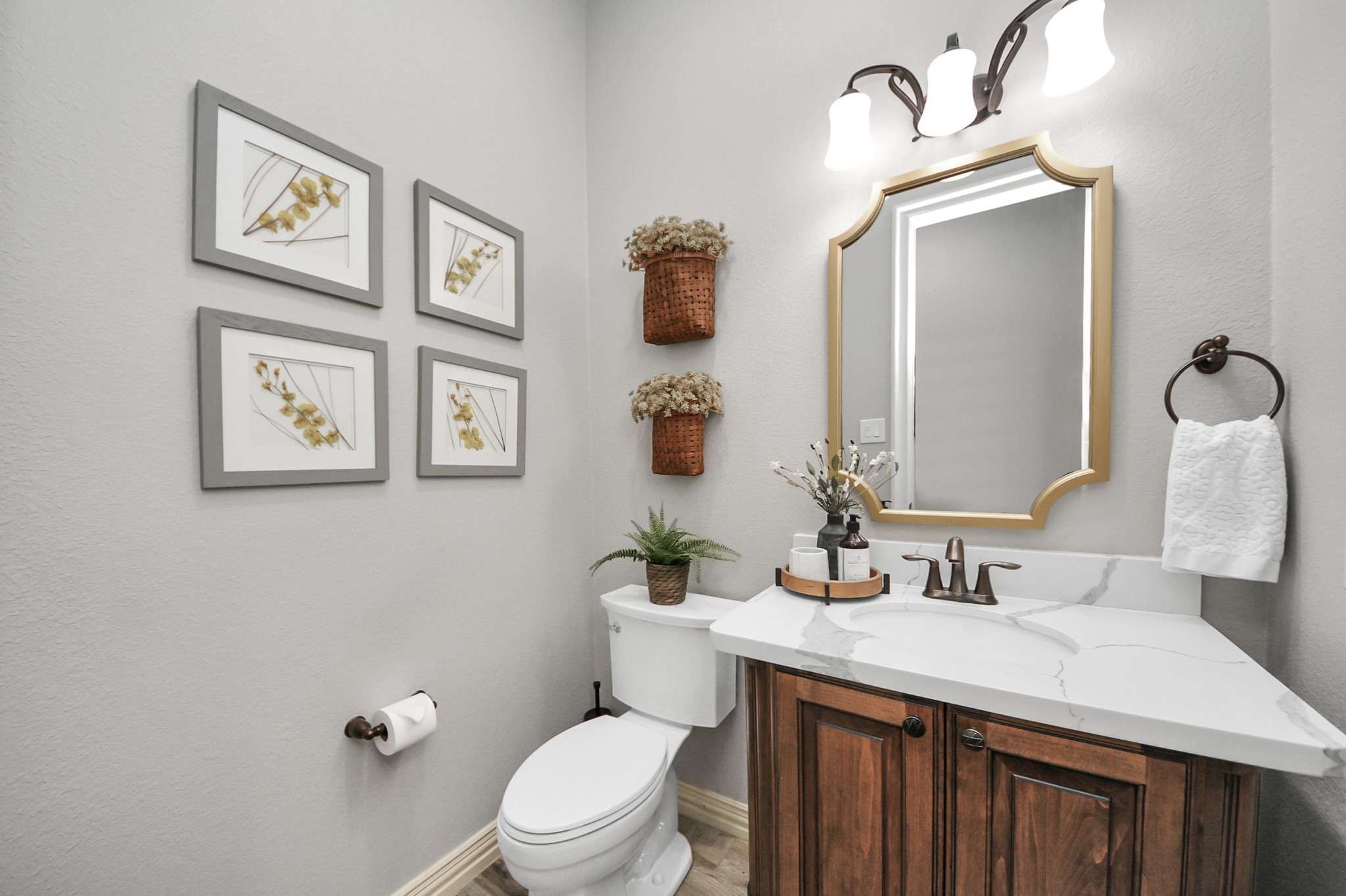 Charming half-bathroom featuring a sleek marble countertop, elegant wooden cabinetry, and stylish wall decor, complemented by warm lighting and contemporary fixtures.