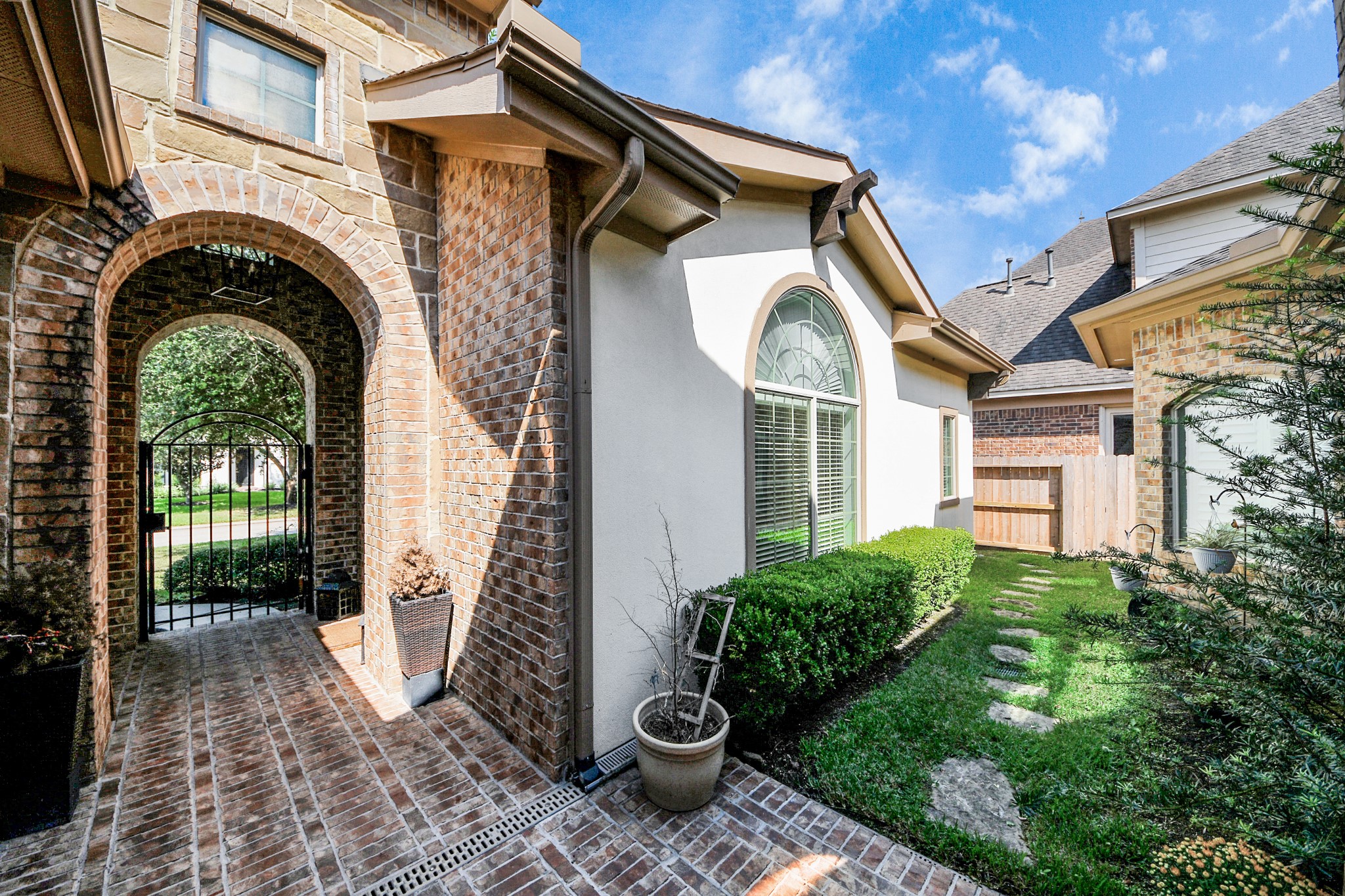 Charming brick archway leads to a gated entrance, complemented by a manicured path and elegant window details, offering a welcoming and secure ambiance. Charming brick archway leads to a gated entrance, complemented by a manicured path and elegant window details, offering a welcoming and secure ambiance.