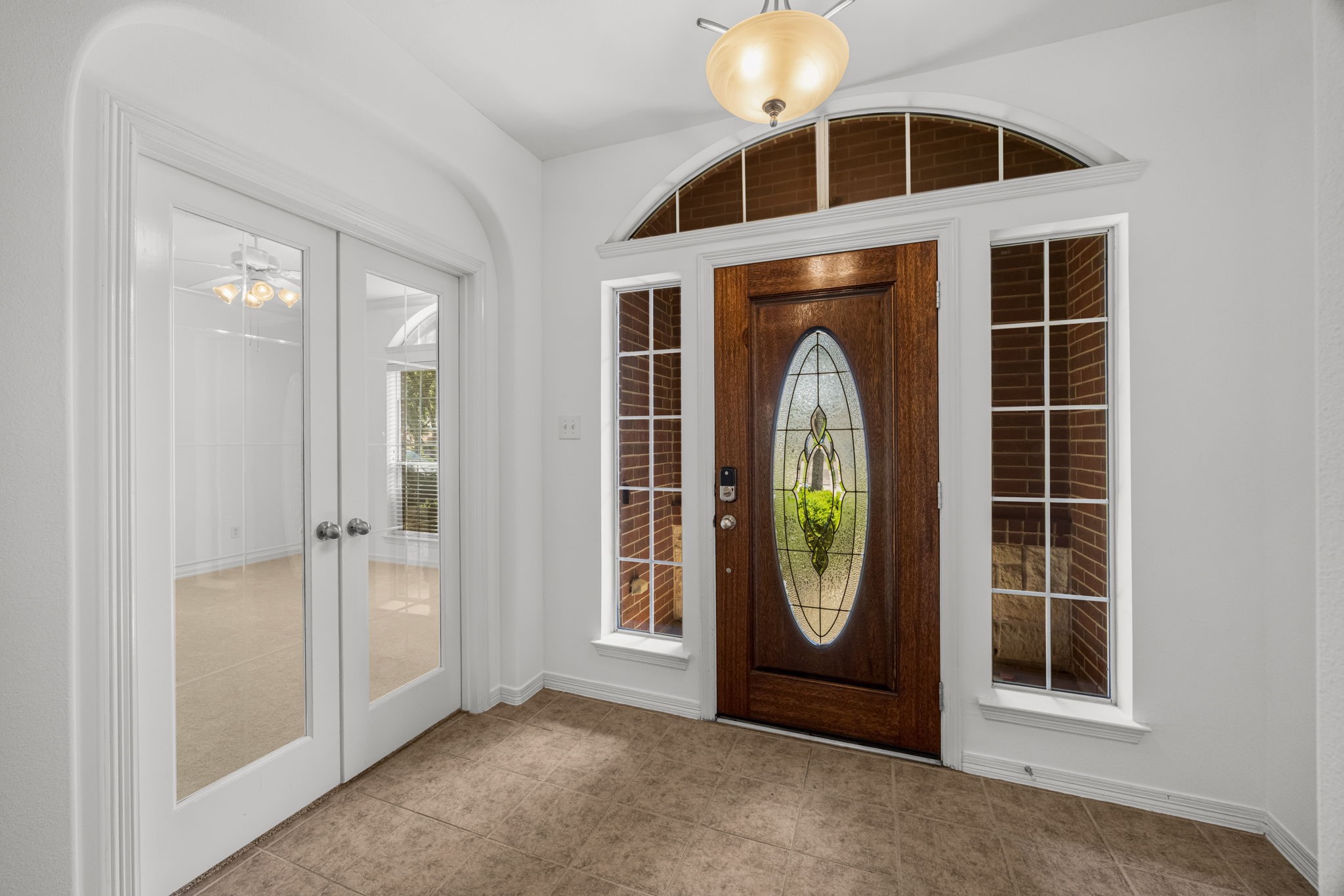An arched transom and sidelights bring added distinction to the front door, while adjacent glass-paneled double doors introduce a private study just off the foyer.