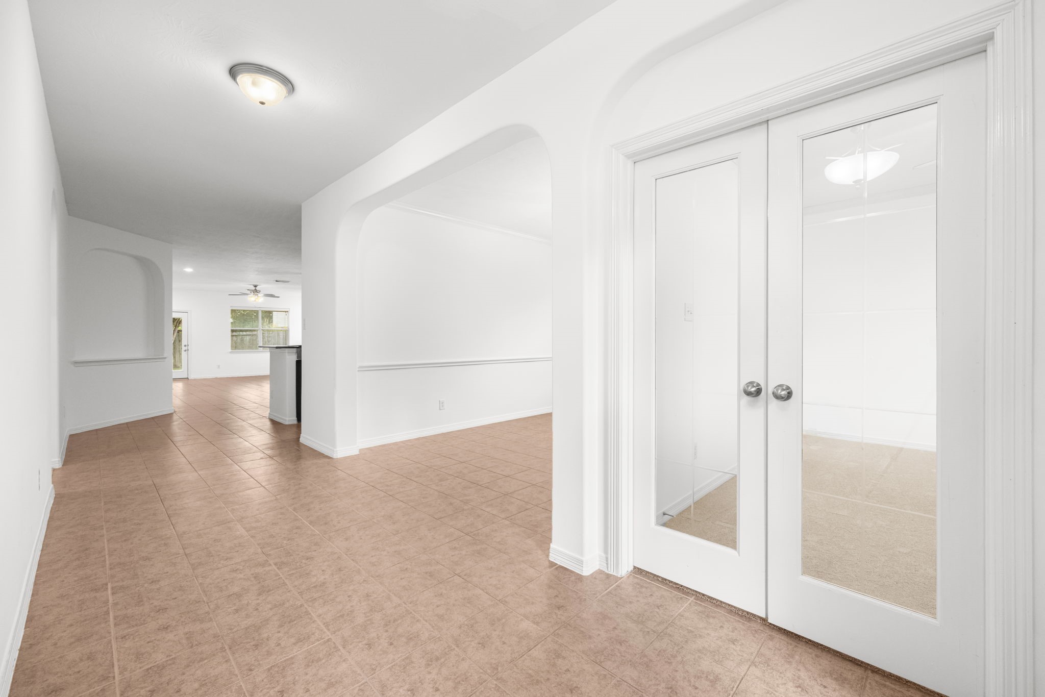 The entry introduces the interior with stylish tiled flooring, a private study, and formal dining room all in view, offering a glimpse of the home's main living spaces beyond.