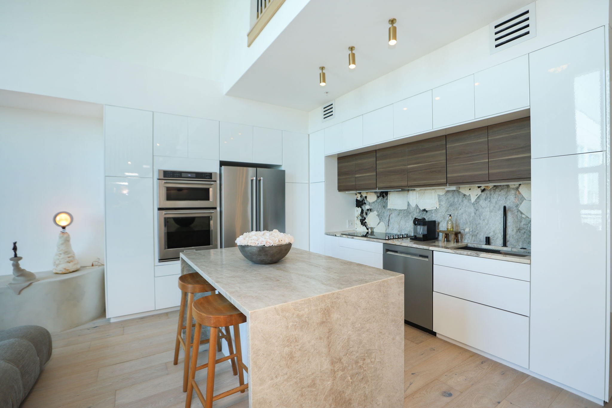 Calcutta Viola marble, waterfall island, sleek high-gloss white cabinetry with contrasting wood-grain accents, and integrated lighting define this gorgeous kitchen. Calcutta Viola marble, waterfall island, sleek high-gloss white cabinetry with contrasting wood-grain accents, and integrated lighting define this gorgeous kitchen.