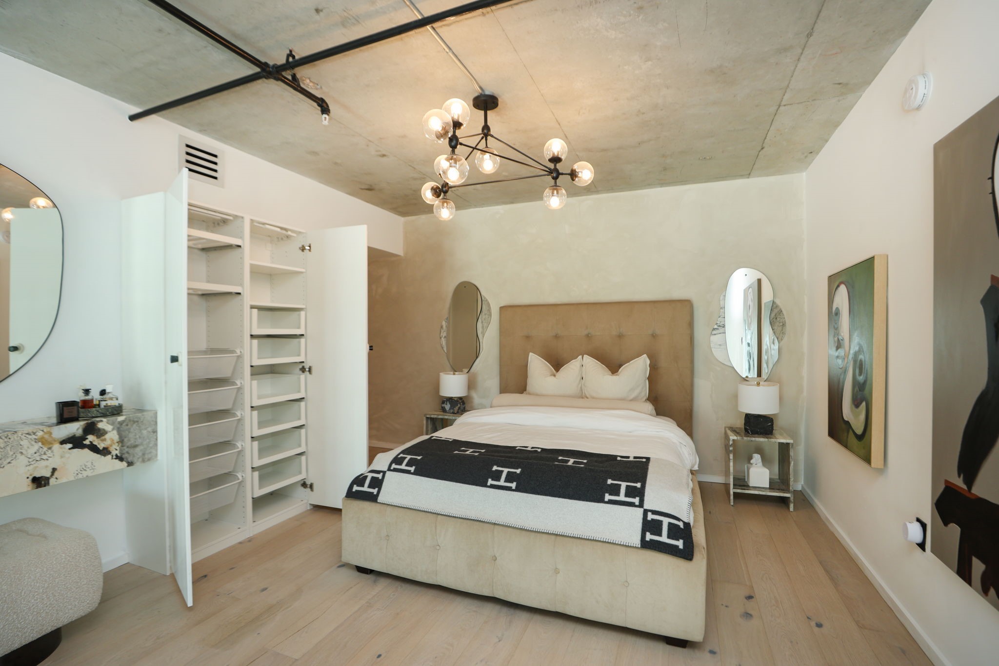 Built-in wardrobe with open shelving and pull out drawers, plus a floating marble vanity, in the primary bedroom.