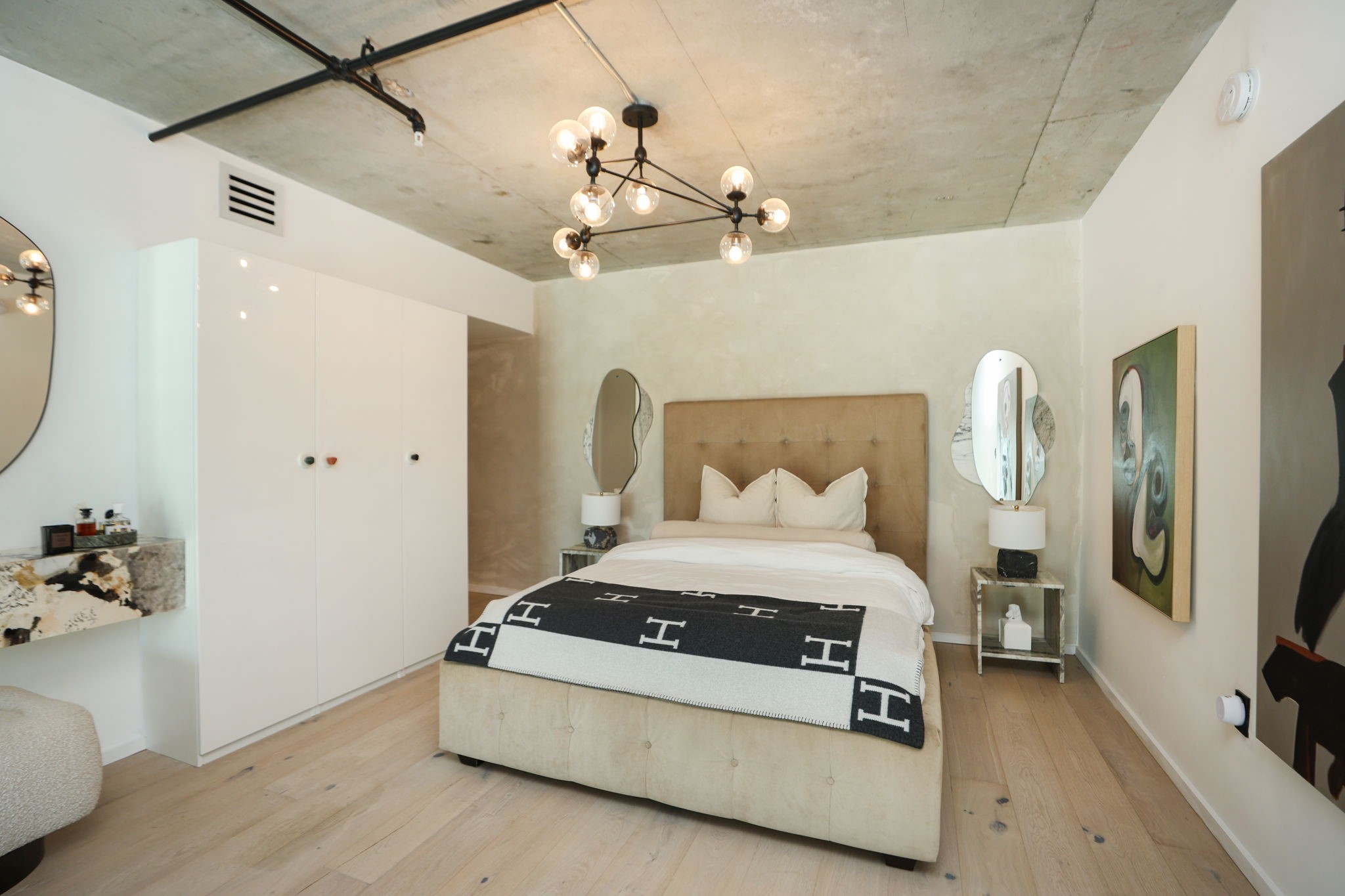 Exposed concrete ceilings and wide-plank flooring set the tone in the primary bedroom, which includes a custom closet system for all of your wardrobe needs.