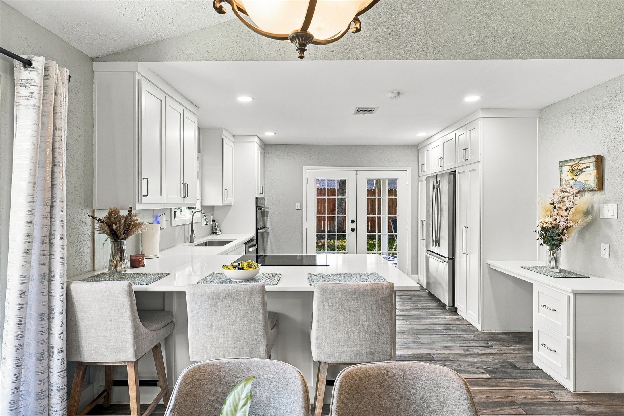Beautifully updated kitchen featuring white cabinetry, quartz countertops, generous counter space, breakfast seating, and recessed lighting.