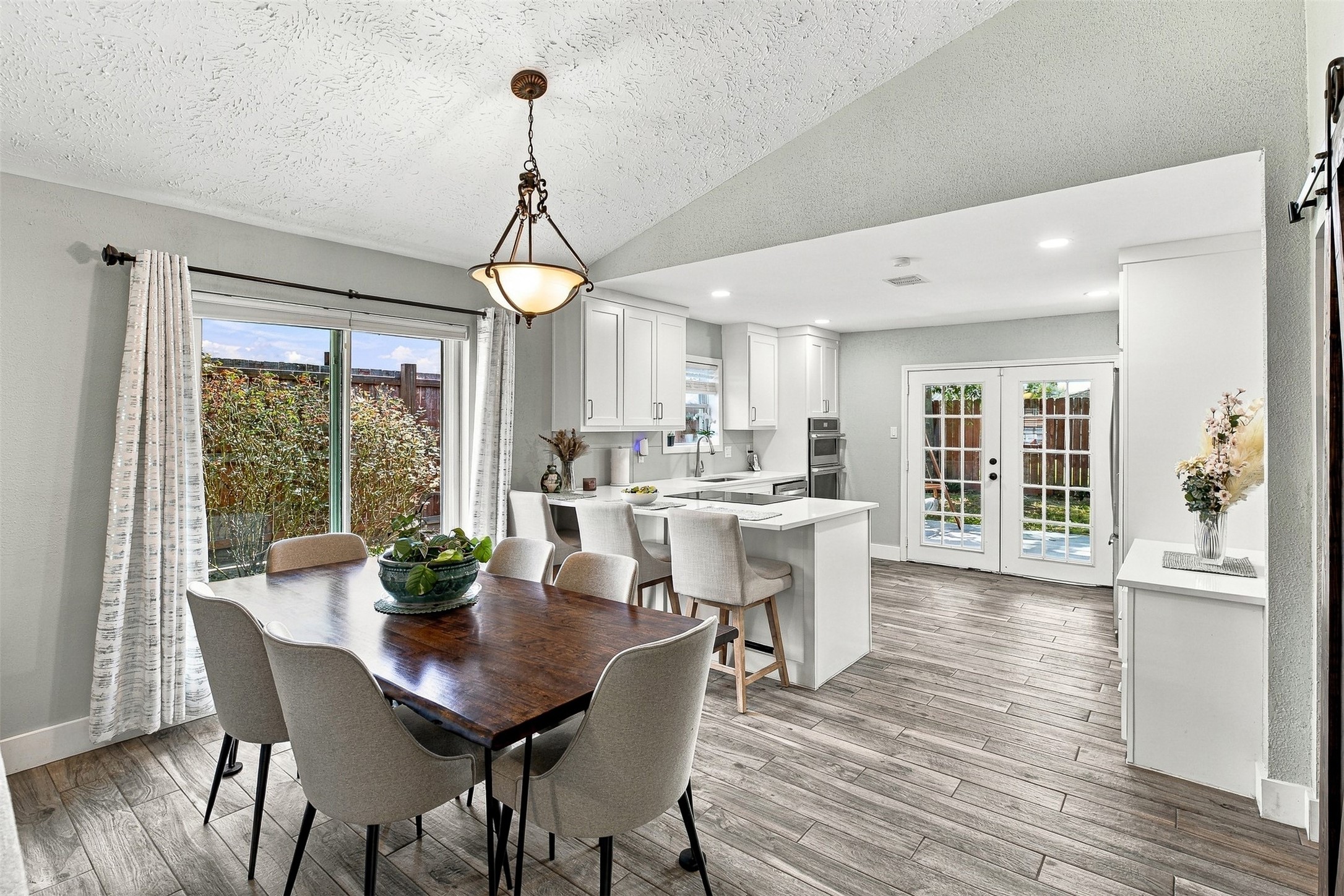 Bright and inviting open-concept living! The dining area flows seamlessly into the beautifully updated kitchen, with vaulted ceilings, abundant natural light, breakfast bar seating, and French doors opening to the backyard.