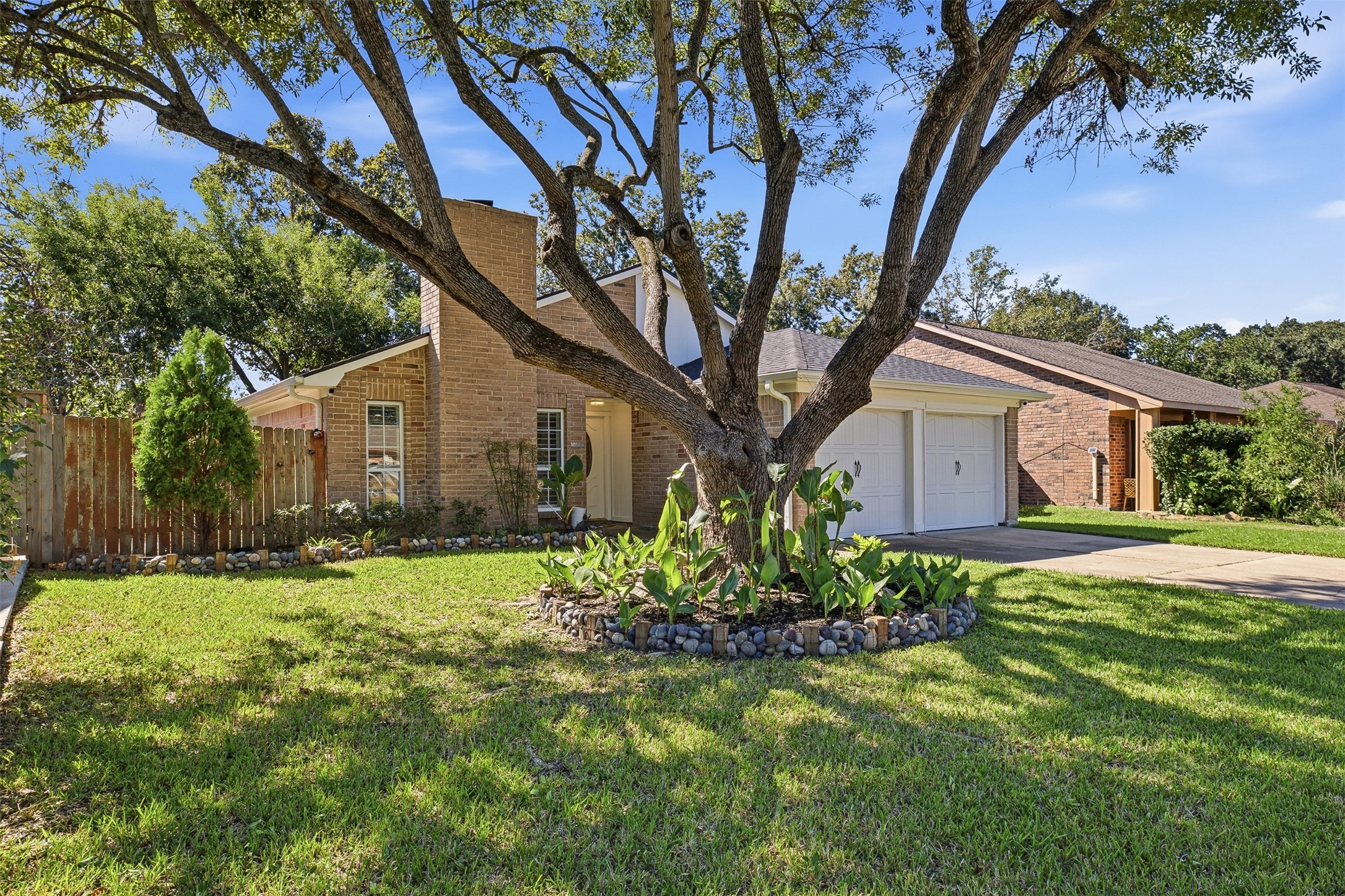 Beautiful brick exterior surrounded by mature trees, manicured landscaping, and an attached two-car garage.