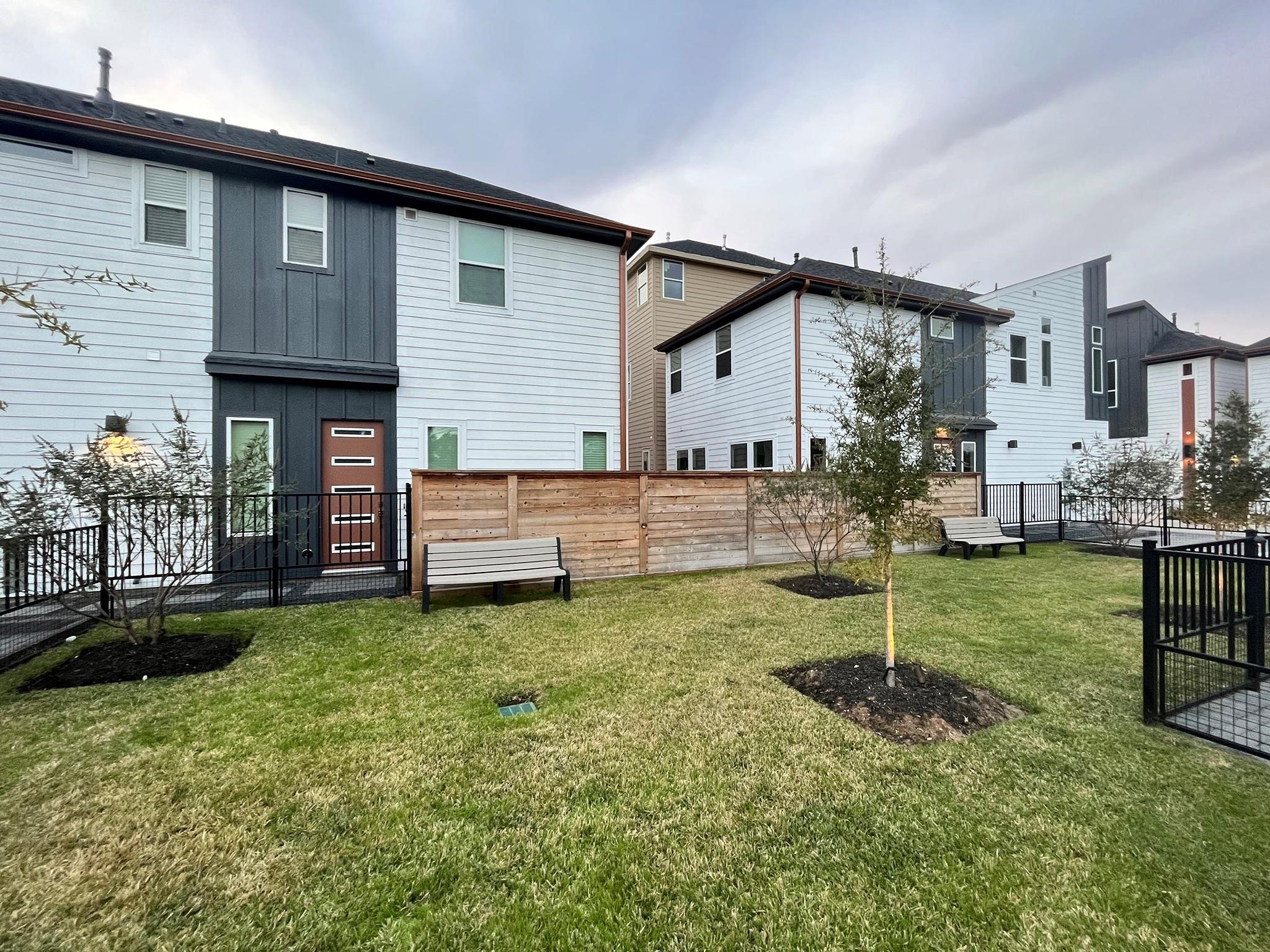 Modern homes with sleek exteriors, fenced yards, and a landscaped communal area featuring benches and trees. 

Note: Photos 2022