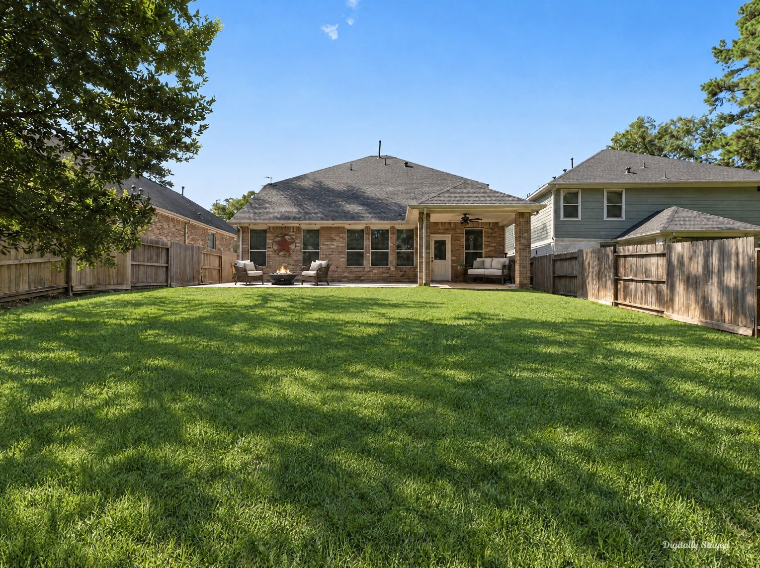 Rear of the home showing a brick exterior, a covered patio, and a wide, level lawn. Full wood fencing and tall trees make the backyard feel open yet private.
This photo has been digitally staged to illustrate the possibilities of the homes aesthetic and potential design. Some furnishings and dcor shown are for visual inspiration.