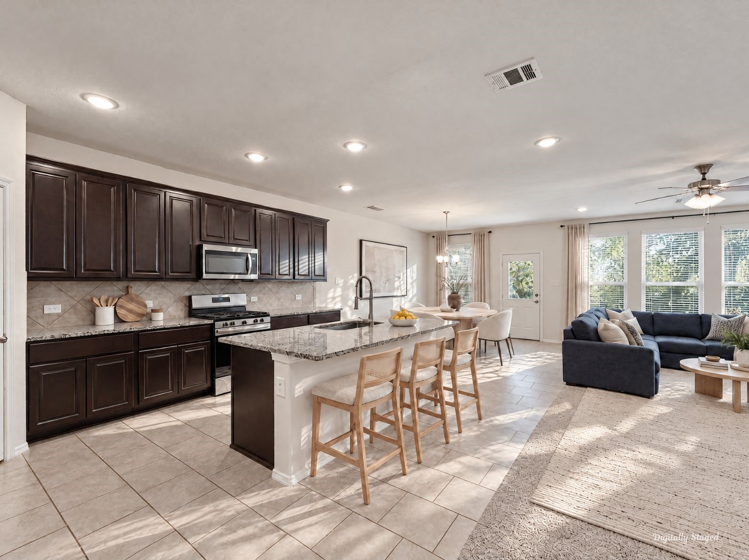 Kitchen flowing openly into the dining and living spaces for a connected main floor. Dark cabinetry and granite counters contrast nicely with the light tile and carpet.
This photo has been digitally staged to illustrate the possibilities of the homes aesthetic and potential design. Some furnishings and dcor shown are for visual inspiration.
