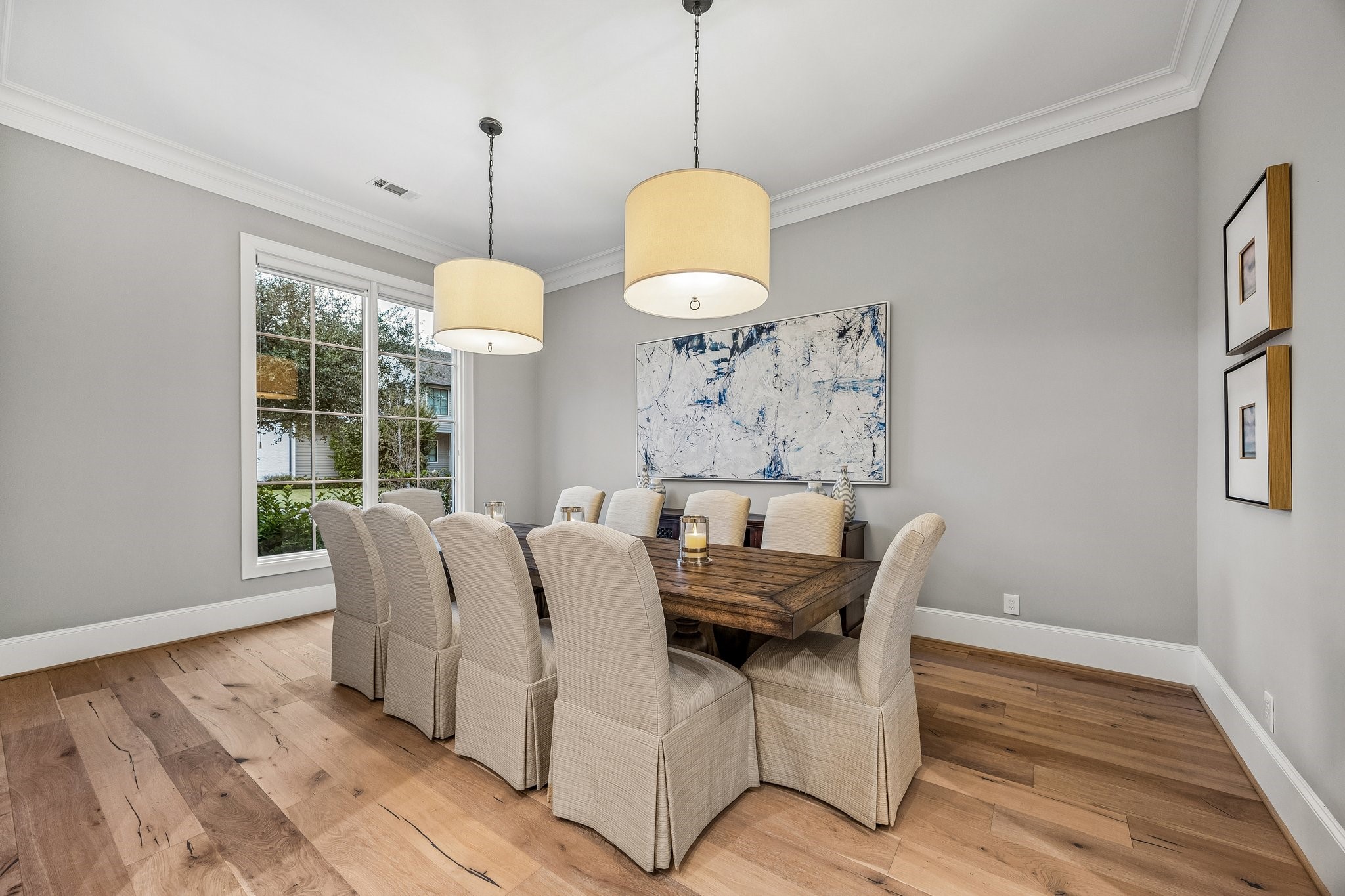 The generously sized dining room features two contemporary drum pendant chandeliers, wide plank floors, crown molding and 8 Inch baseboards.